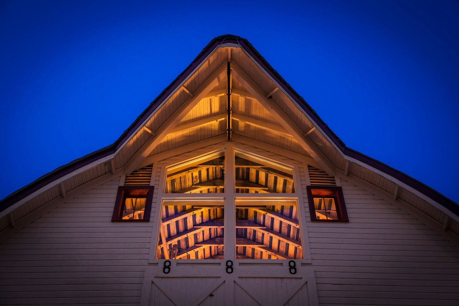 Illuminated barn venue exterior with warm golden lights against deep blue twilight sky.
