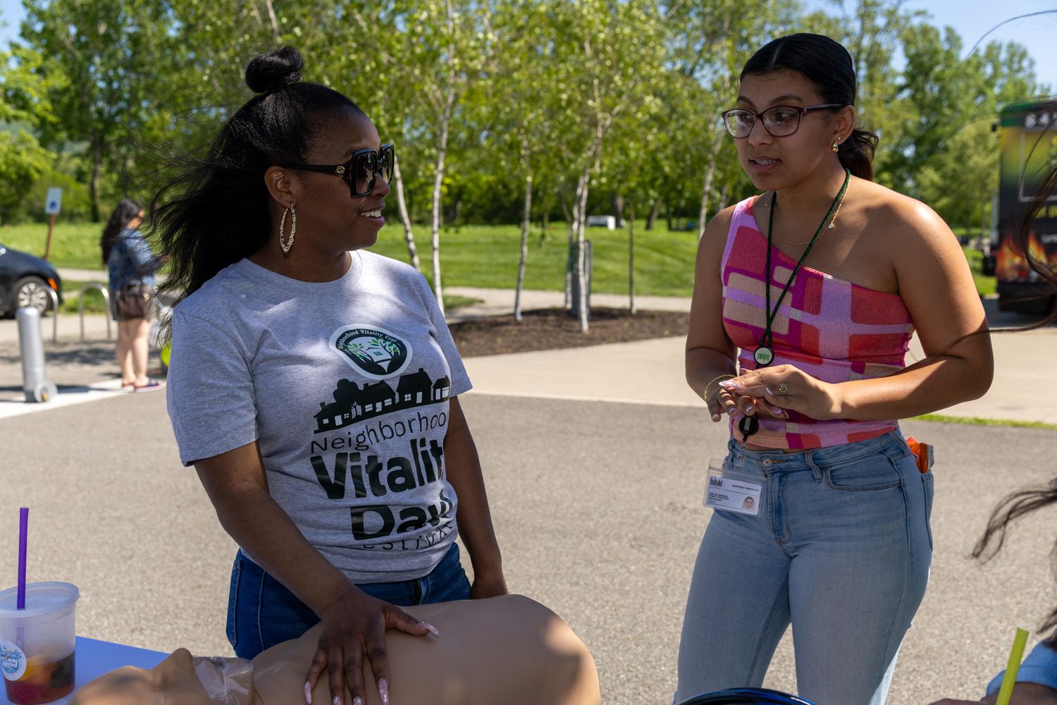 Two women having a conversation at an outdoor community health and vitality day event.