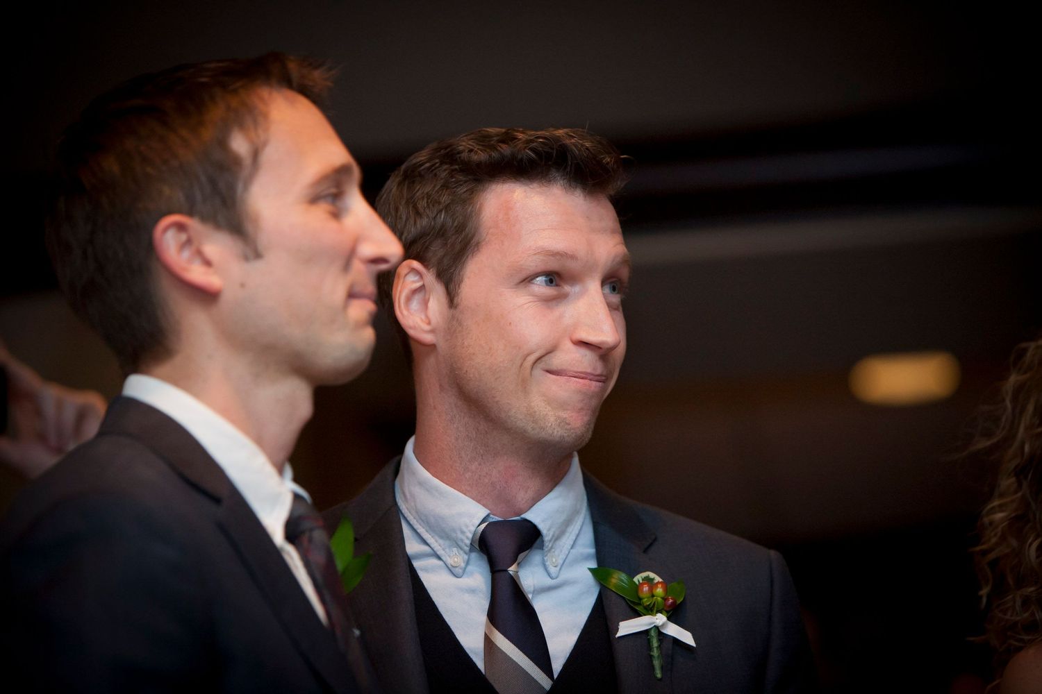 Two grooms sharing an emotional moment during their wedding ceremony, one whispering to the other.