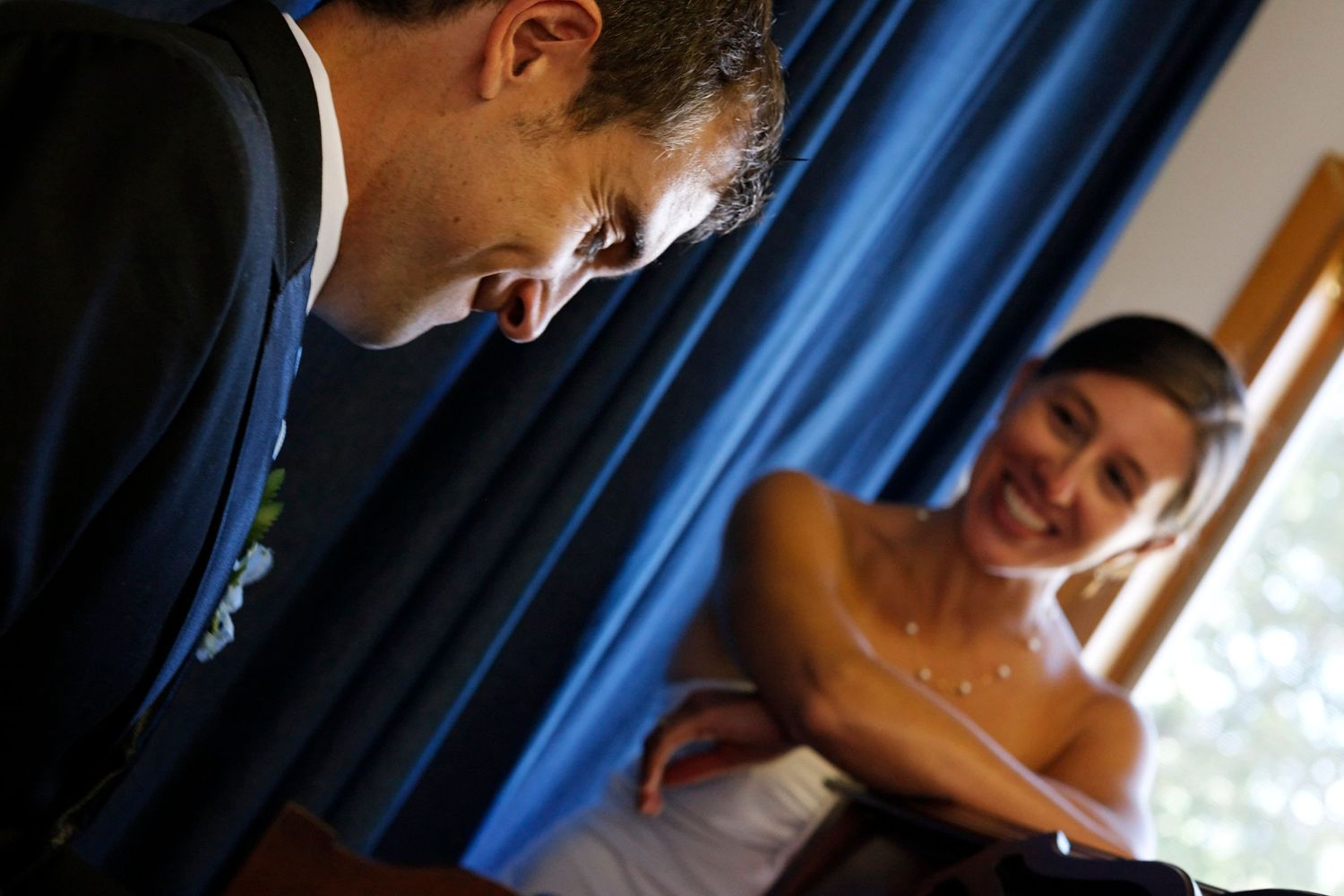 Groom exchanging wedding rings with smiling bride during intimate ceremony indoors.