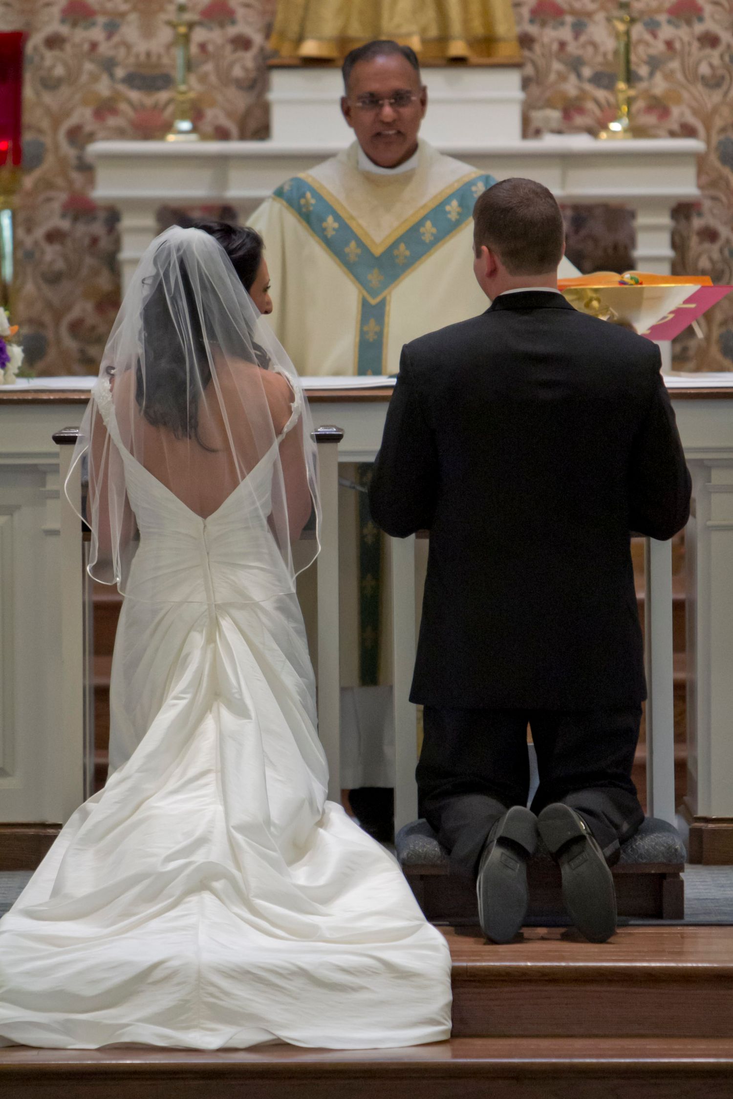A bride and groom kneeling at the altar during a church wedding ceremony.