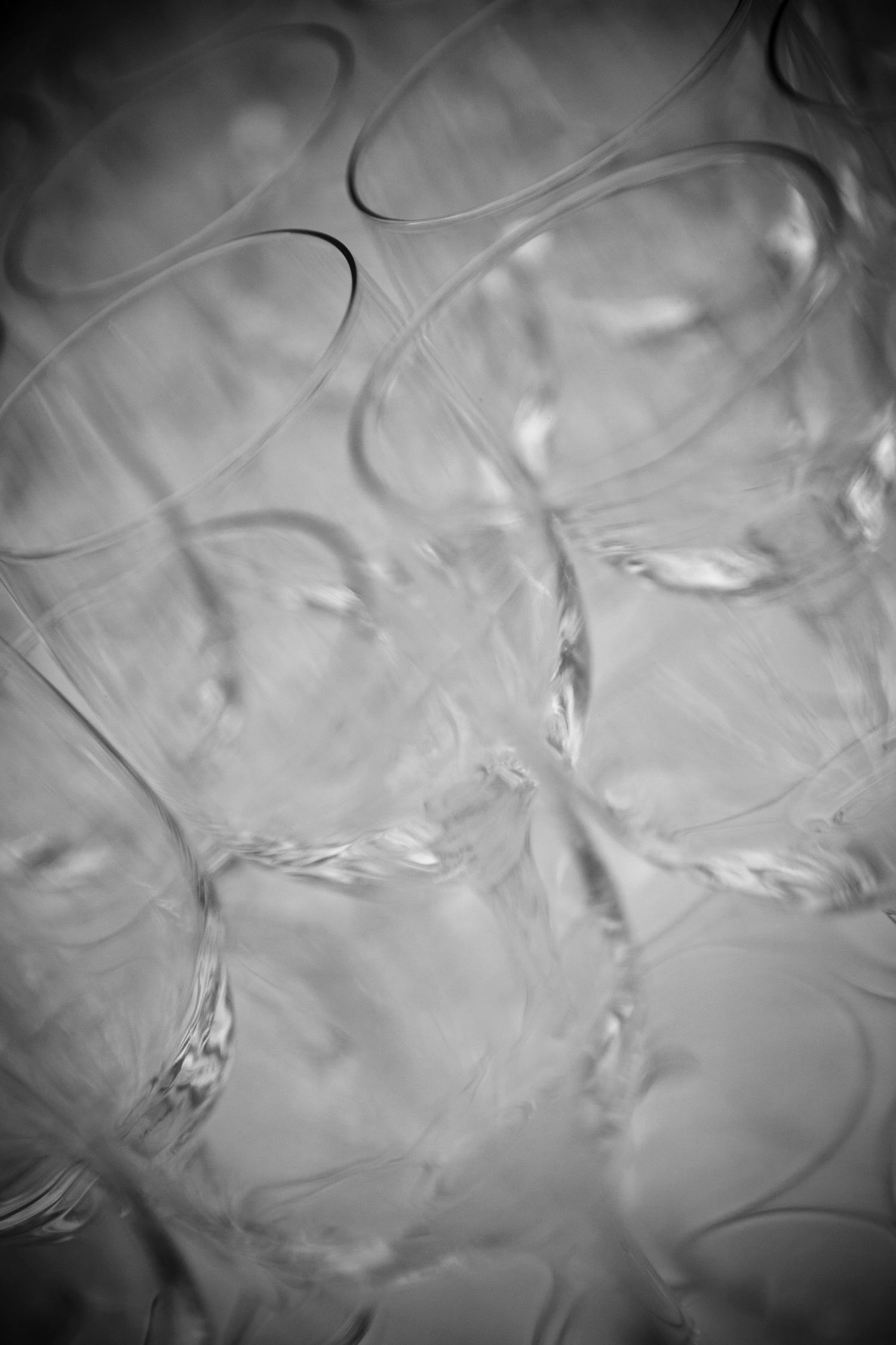 Abstract black and white close-up of stacked crystal wine glasses creating elegant patterns.