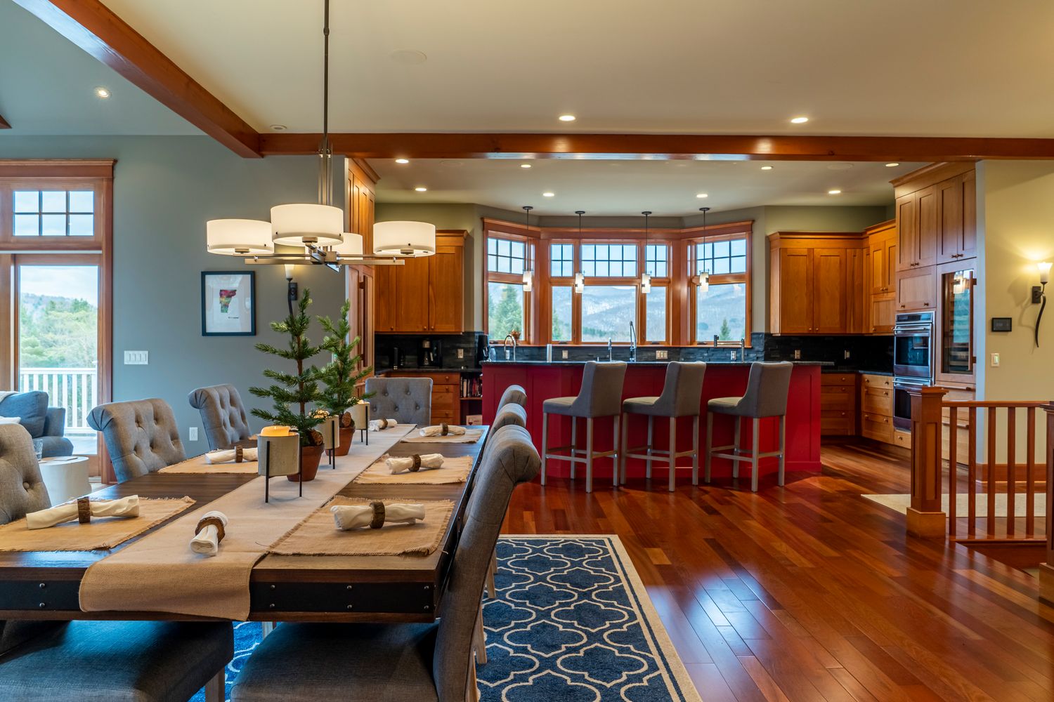 Open-concept kitchen and dining room with hardwood floors, red kitchen island, pendant lighting, and wood cabinetry.
