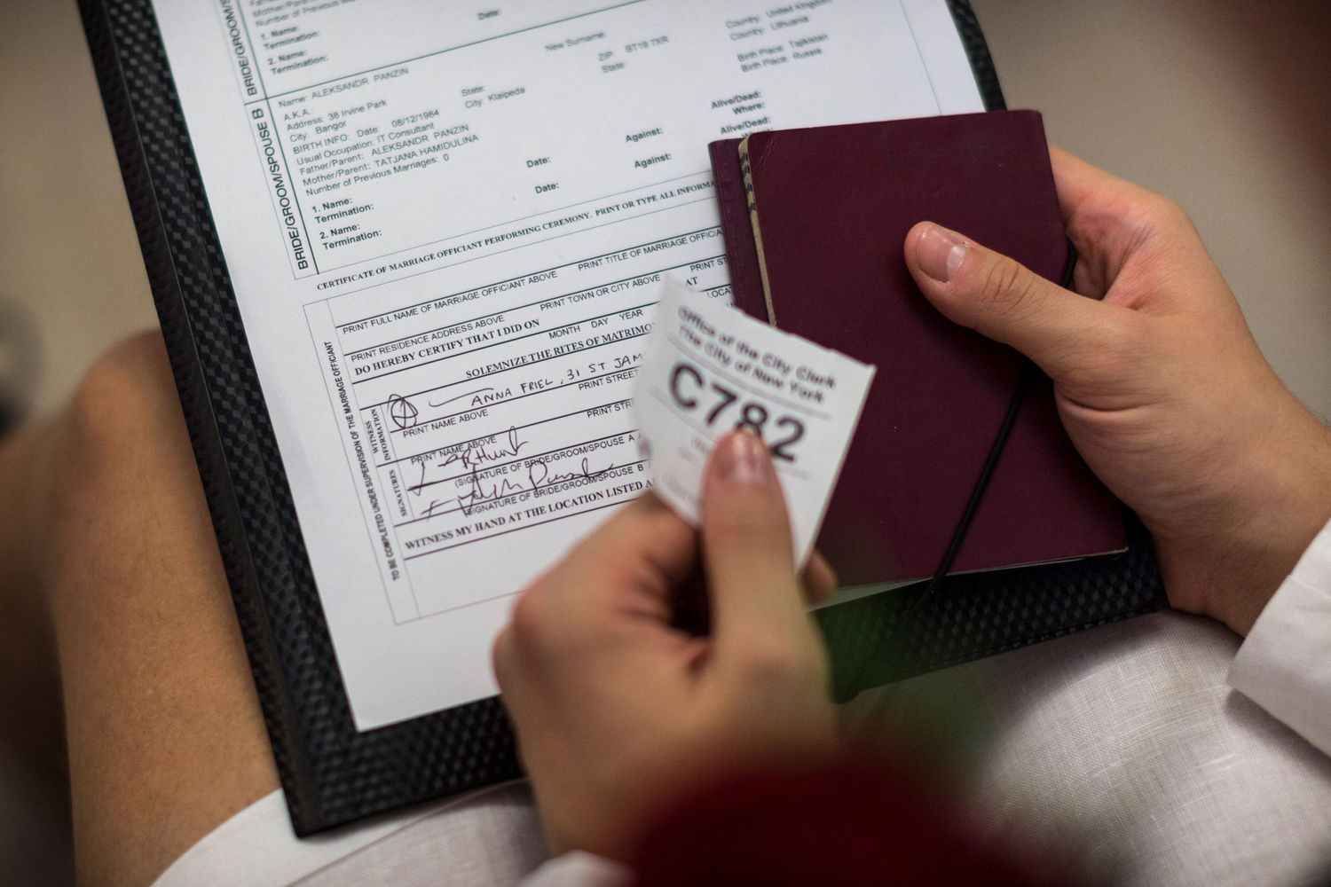 Person holding passport, boarding pass C782, and immigration form on clipboard for international travel.