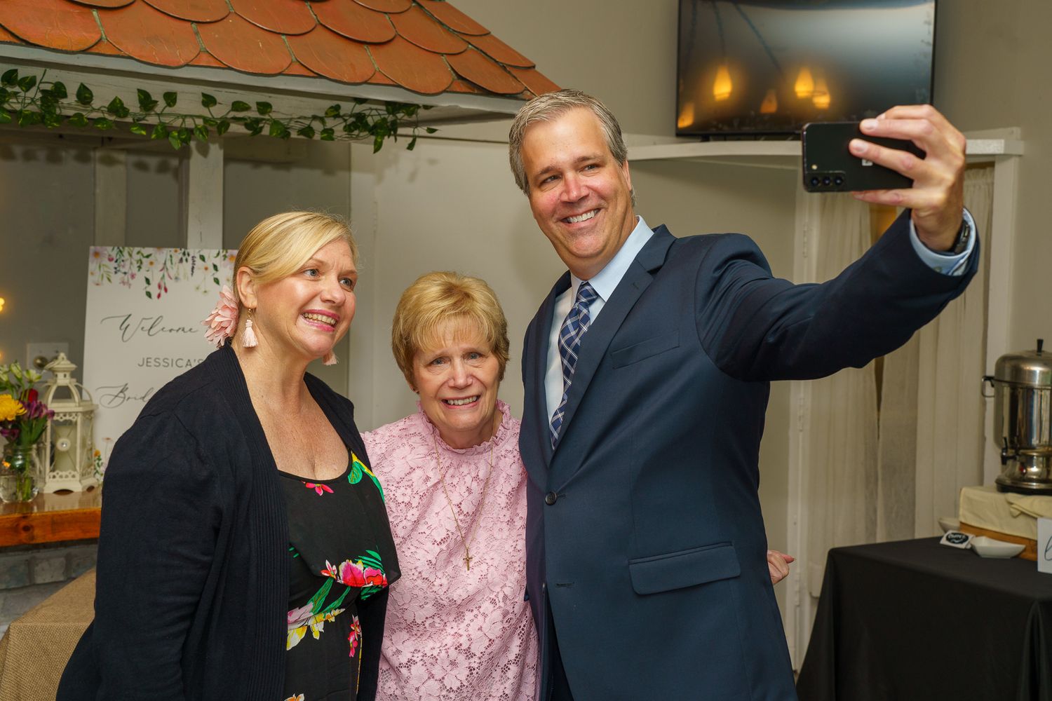 Three adults taking a selfie together at an indoor celebration event.