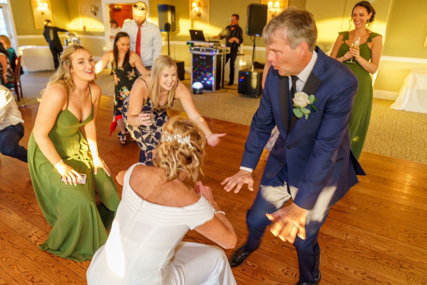 Bride and groom dancing energetically with bridesmaids in green dresses at a lively wedding reception.
