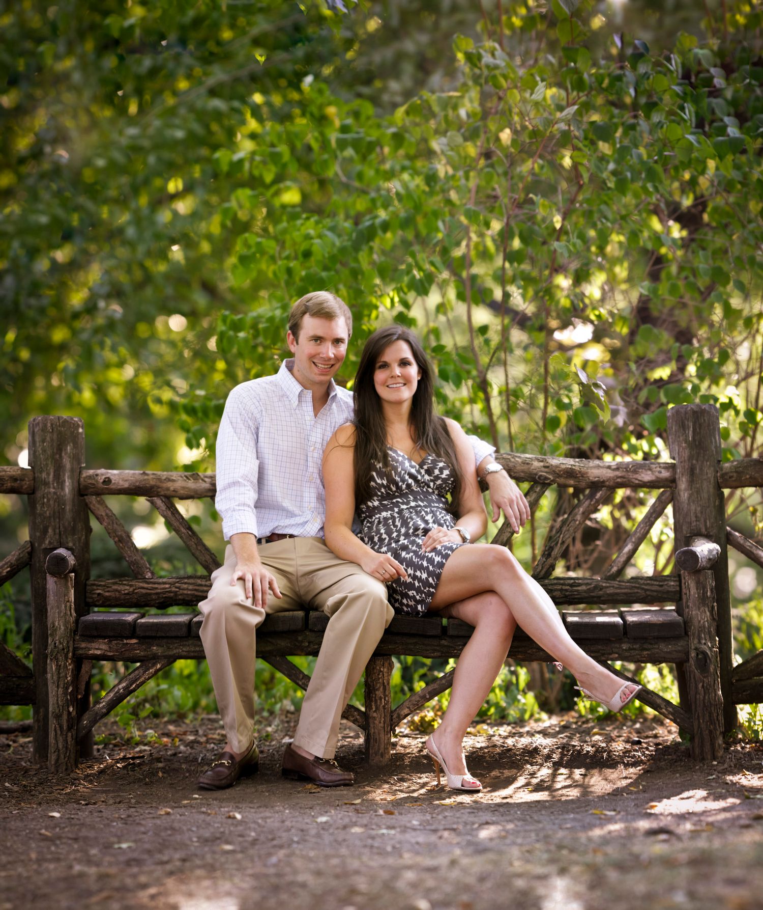 Couple sitting together on rustic wooden bench in lush green park setting.