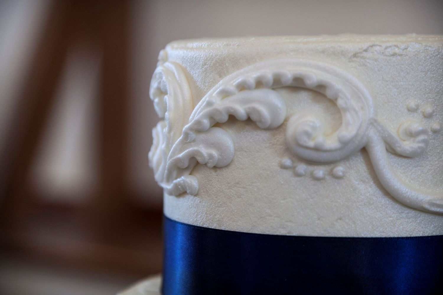 Close-up of elegant white wedding cake tier with intricate scroll fondant details.