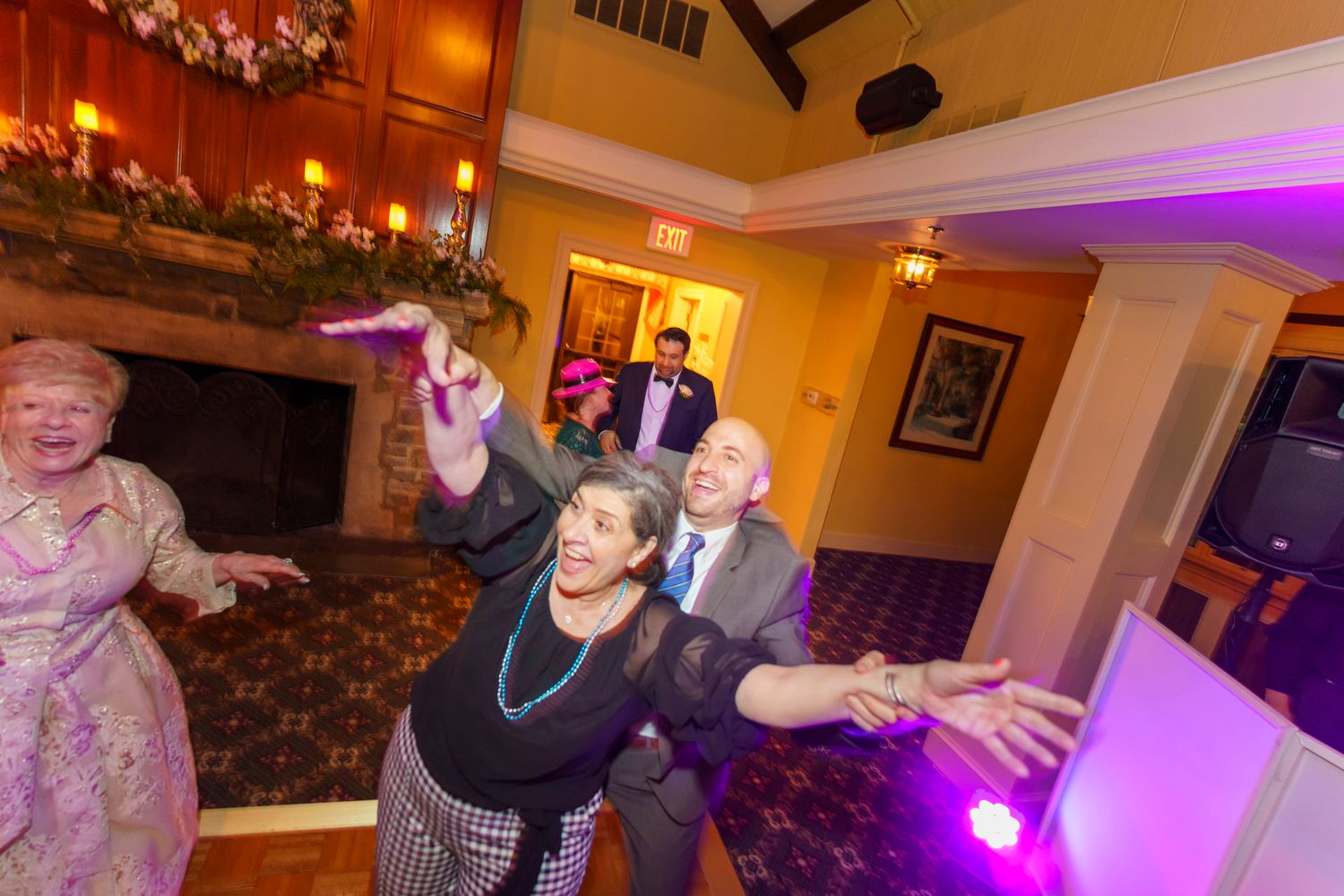 Guests dance and pose energetically on the dance floor at an elegant wedding reception venue.