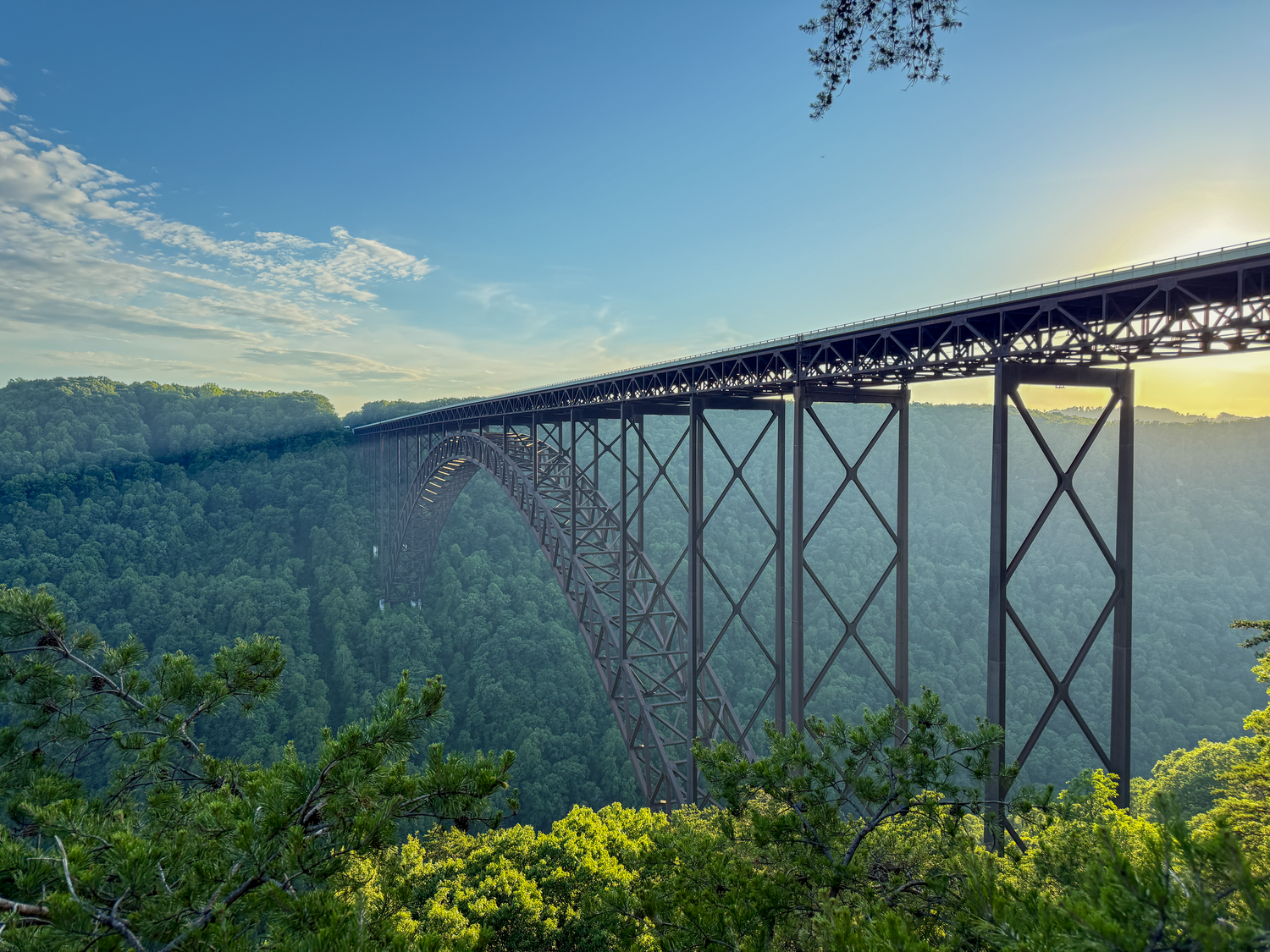 New River Gorge Bridge spanning a lush forested canyon at sunset in West Virginia.