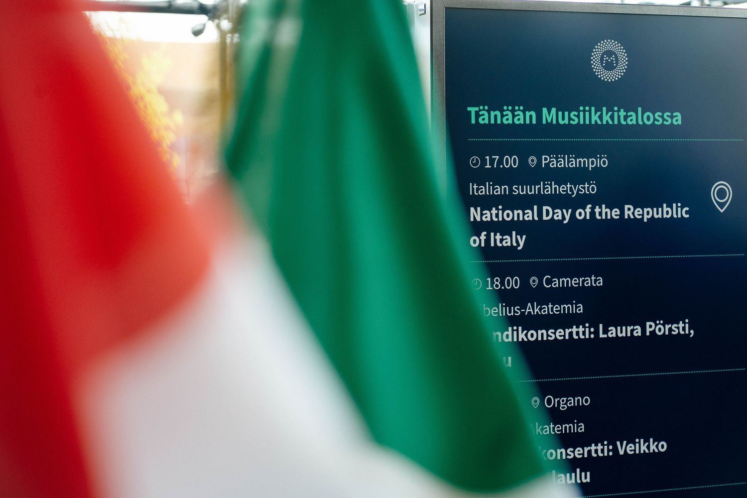 Italian flag beside National Day of the Republic of Italy event schedule board.