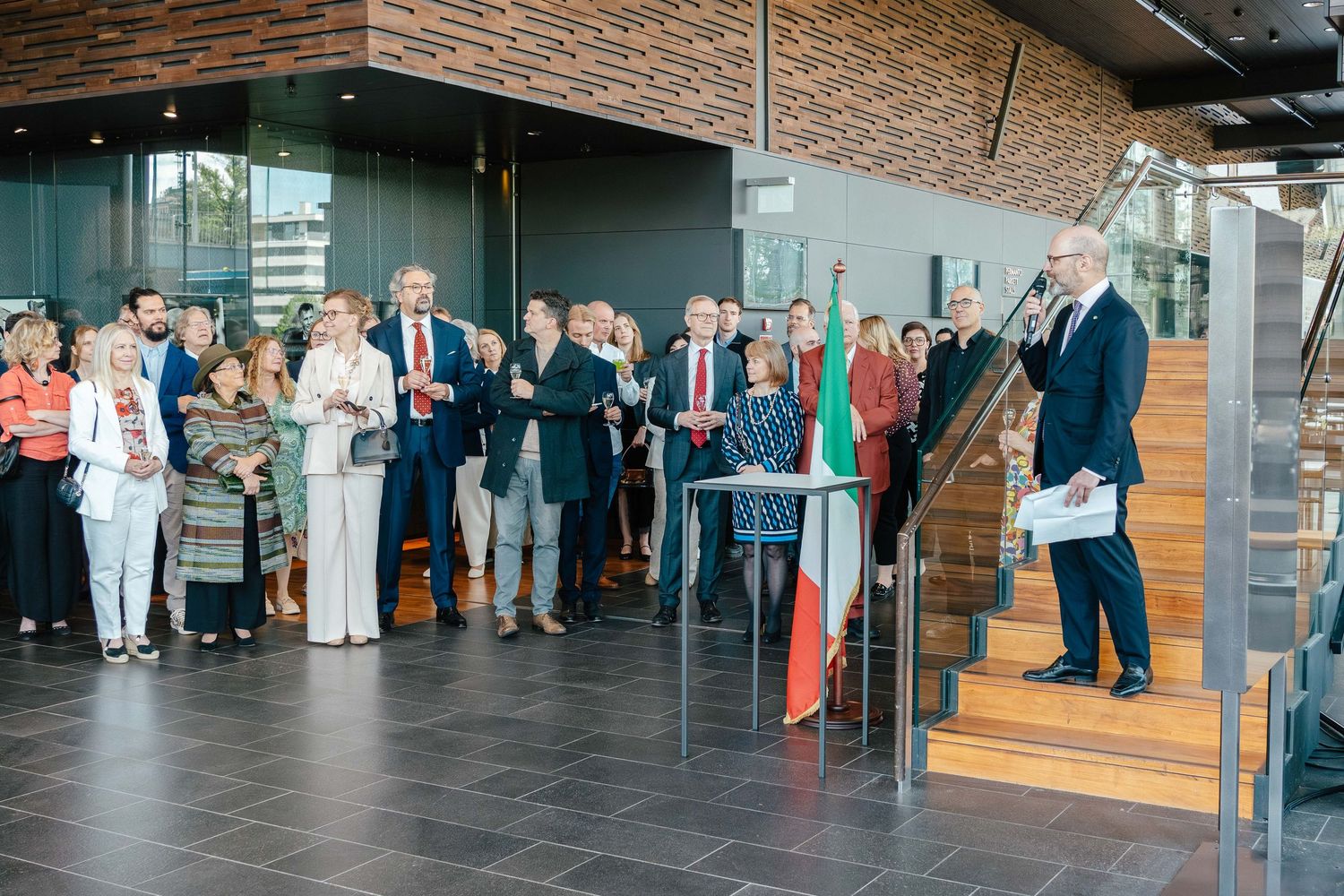 Attendees gathered at Italian National Day reception with speaker on staircase.
