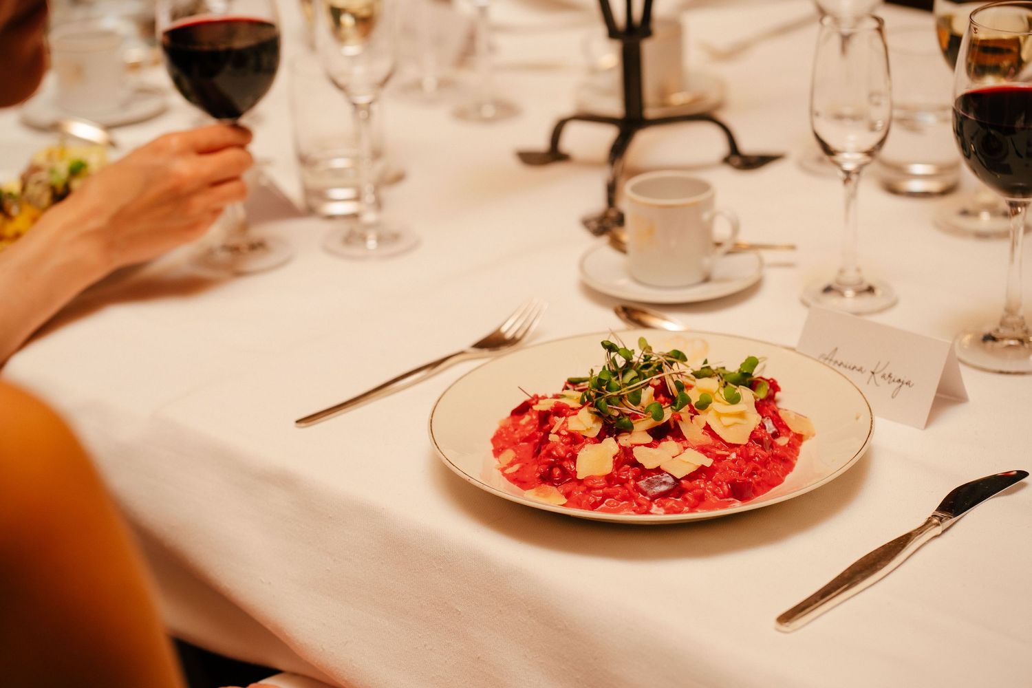 Elegant plated carpaccio dish with garnish on white tablecloth at formal dinner event.
