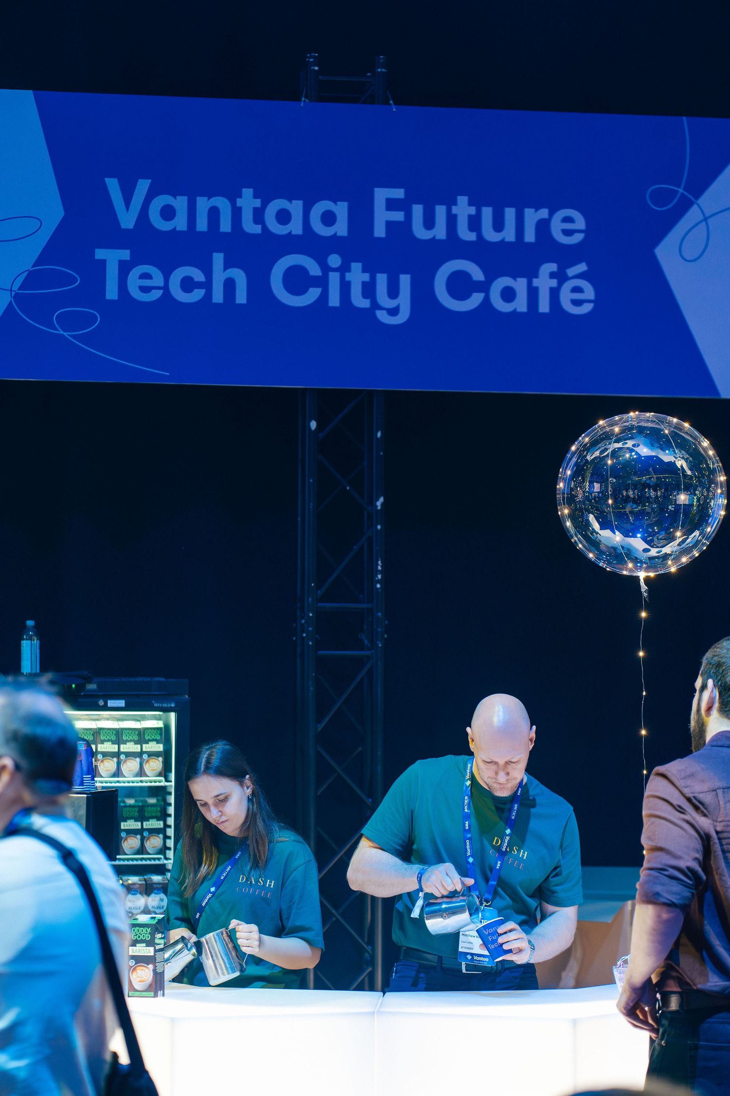 Vantaa Future Tech City Café sign with baristas preparing coffee at tech event.