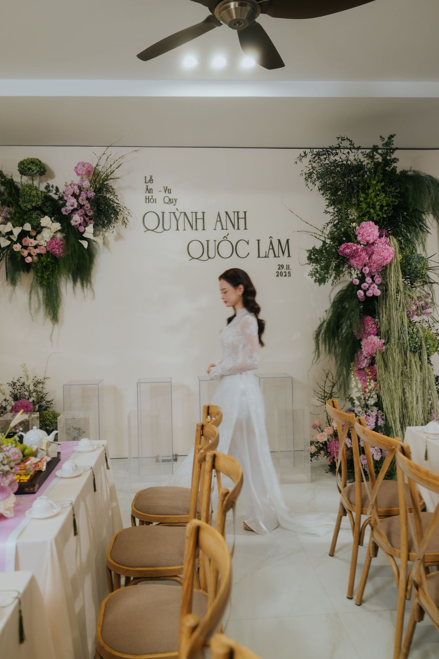 Elegant wedding venue decorated with lush floral arrangements for Quynh Anh and Quoc Lam, bride in white outfit.