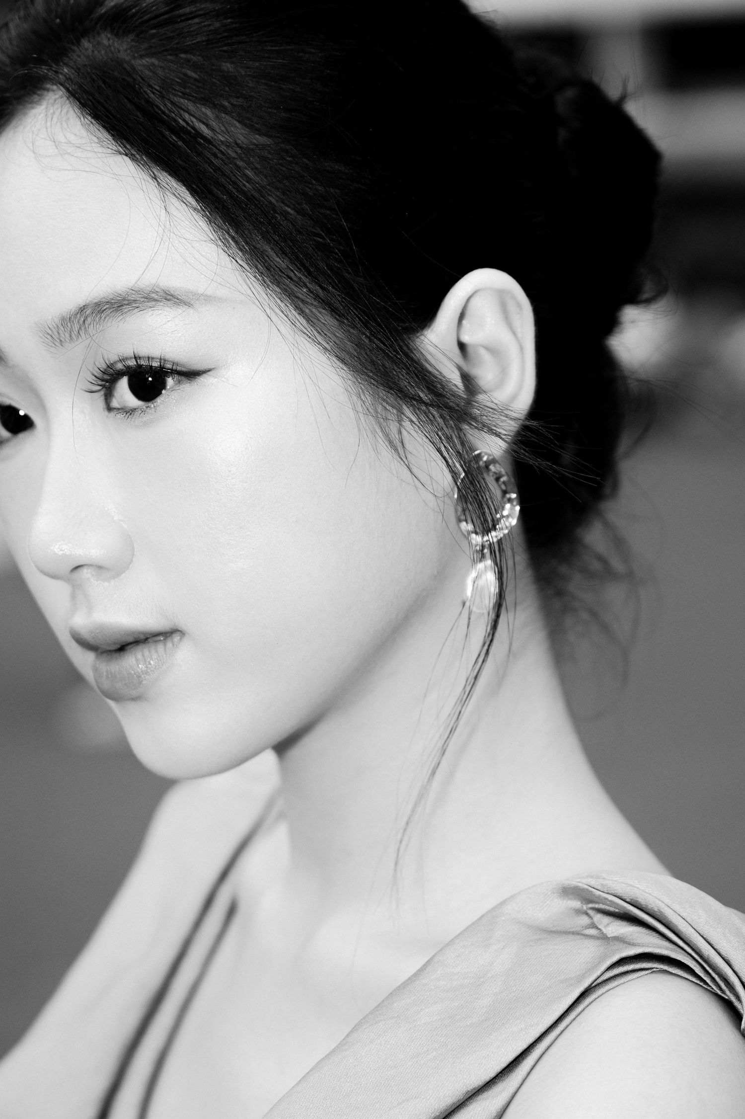 Black and white portrait of a young Asian woman with elegant updo hairstyle and decorative ear cuff earring.