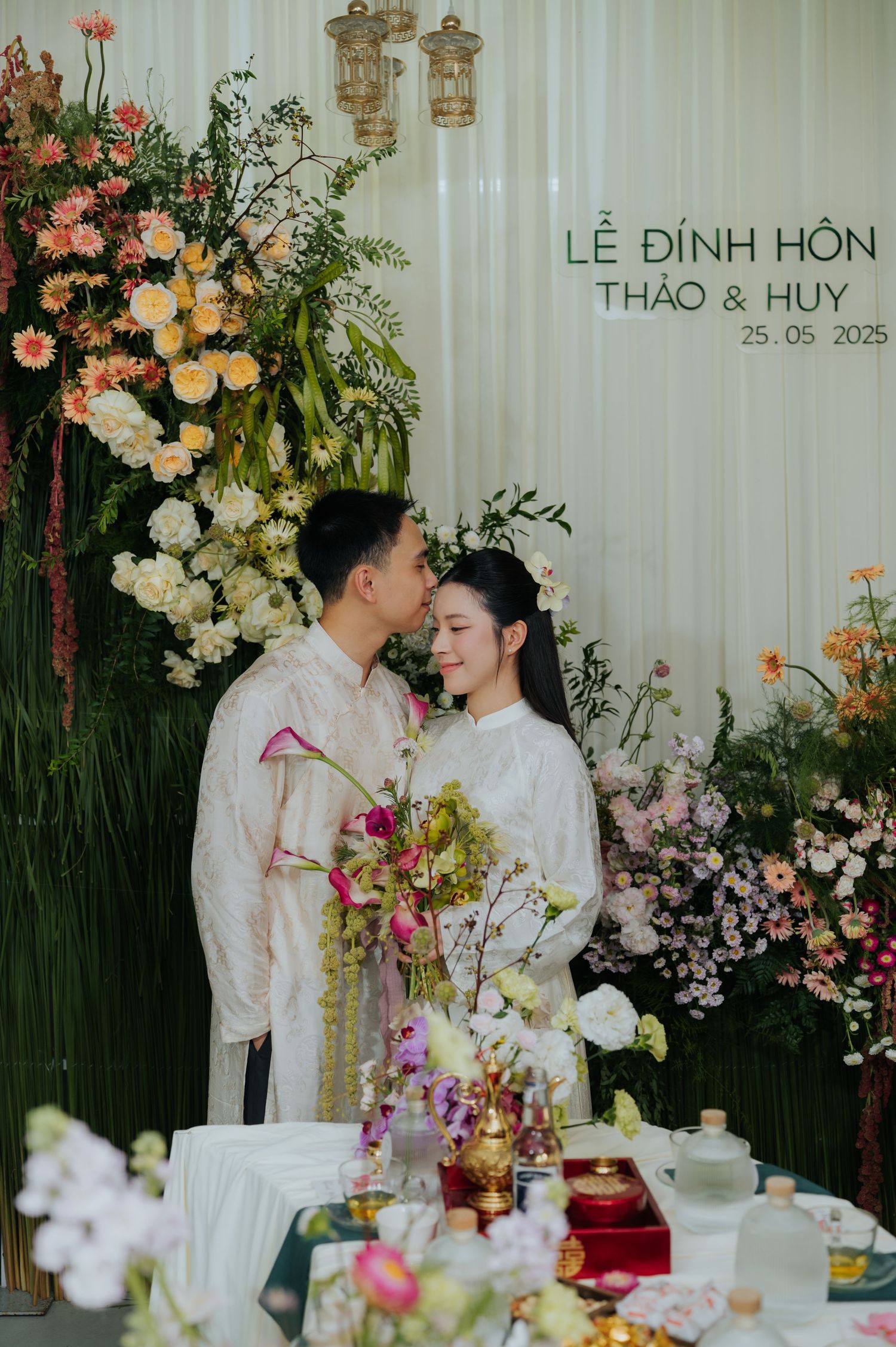 Vietnamese couple in traditional ao dai attire share a tender moment at their Le Dinh Hon engagement ceremony on 25.05.2025.