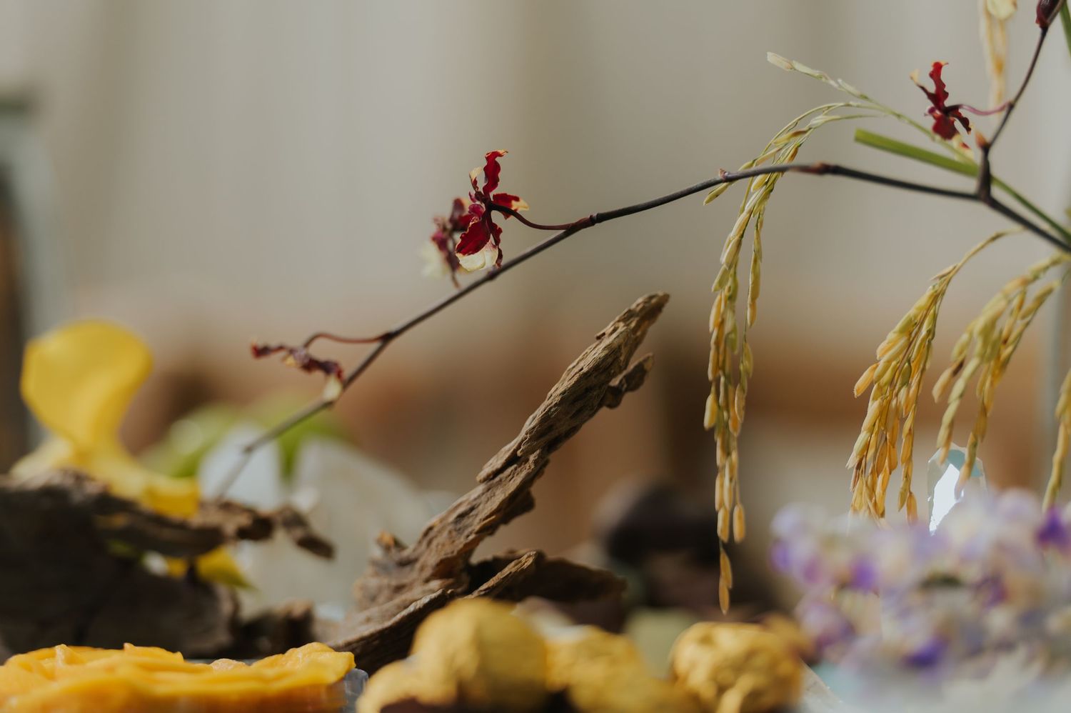 Close-up of dried botanicals arrangement featuring red berries, wheat stalks, and yellow dried flowers.