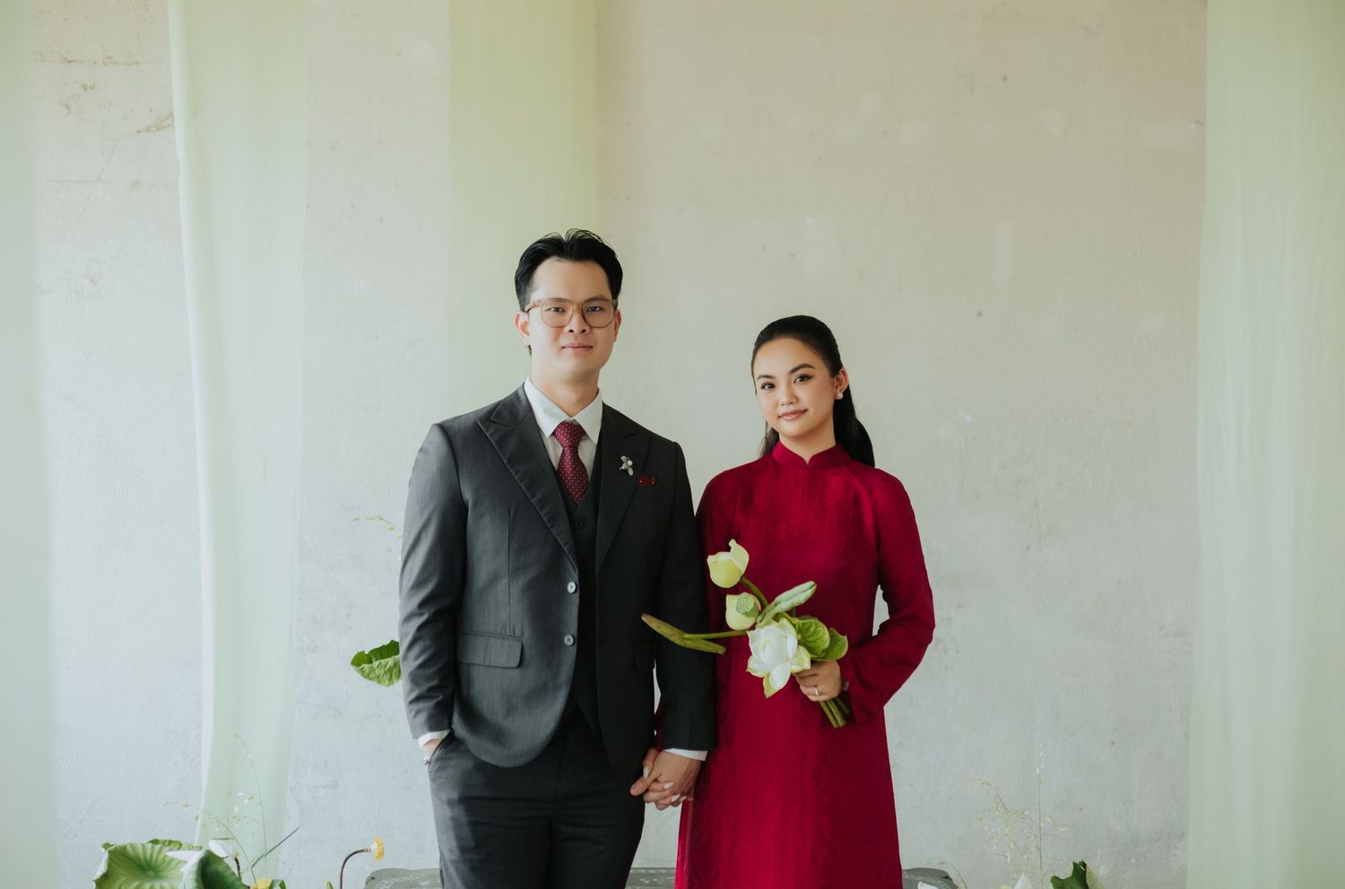 Couple posing in traditional Vietnamese ao dai and suit for a formal portrait photo.