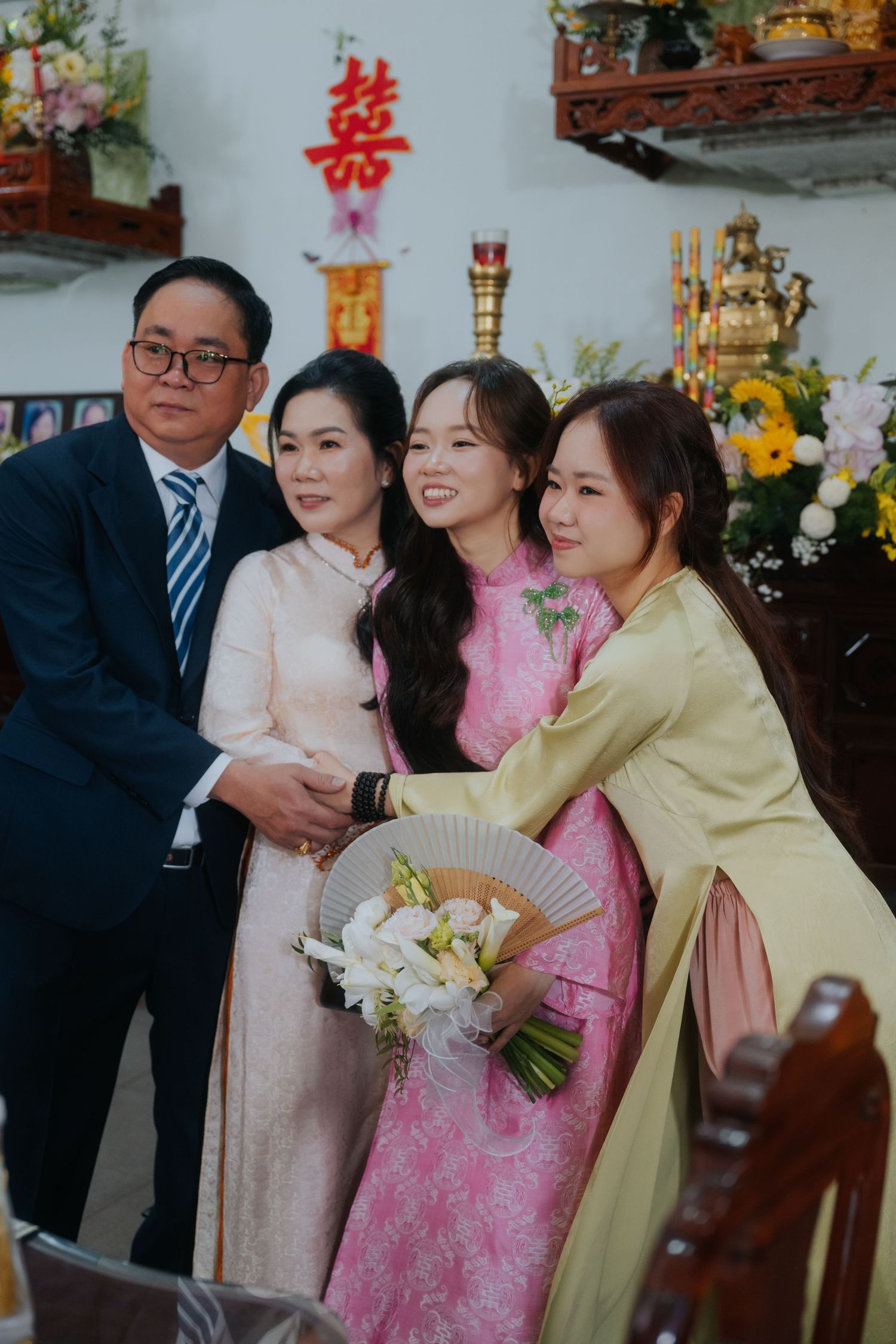 Family posing together at a Vietnamese wedding ceremony, wearing traditional ao dai and formal attire.