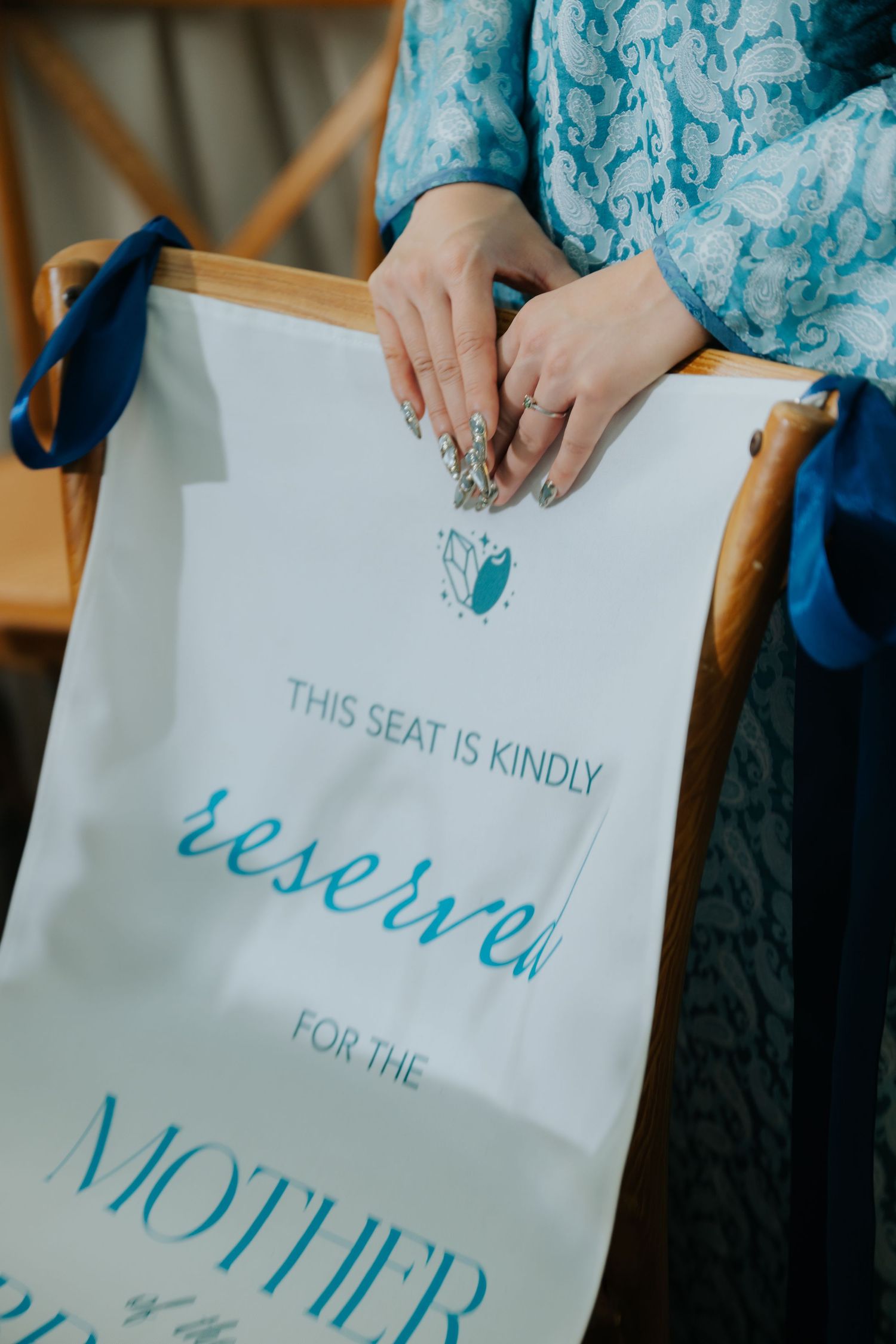 Woman holding a reserved seat sign for the Mother of the Bride at a wedding ceremony.
