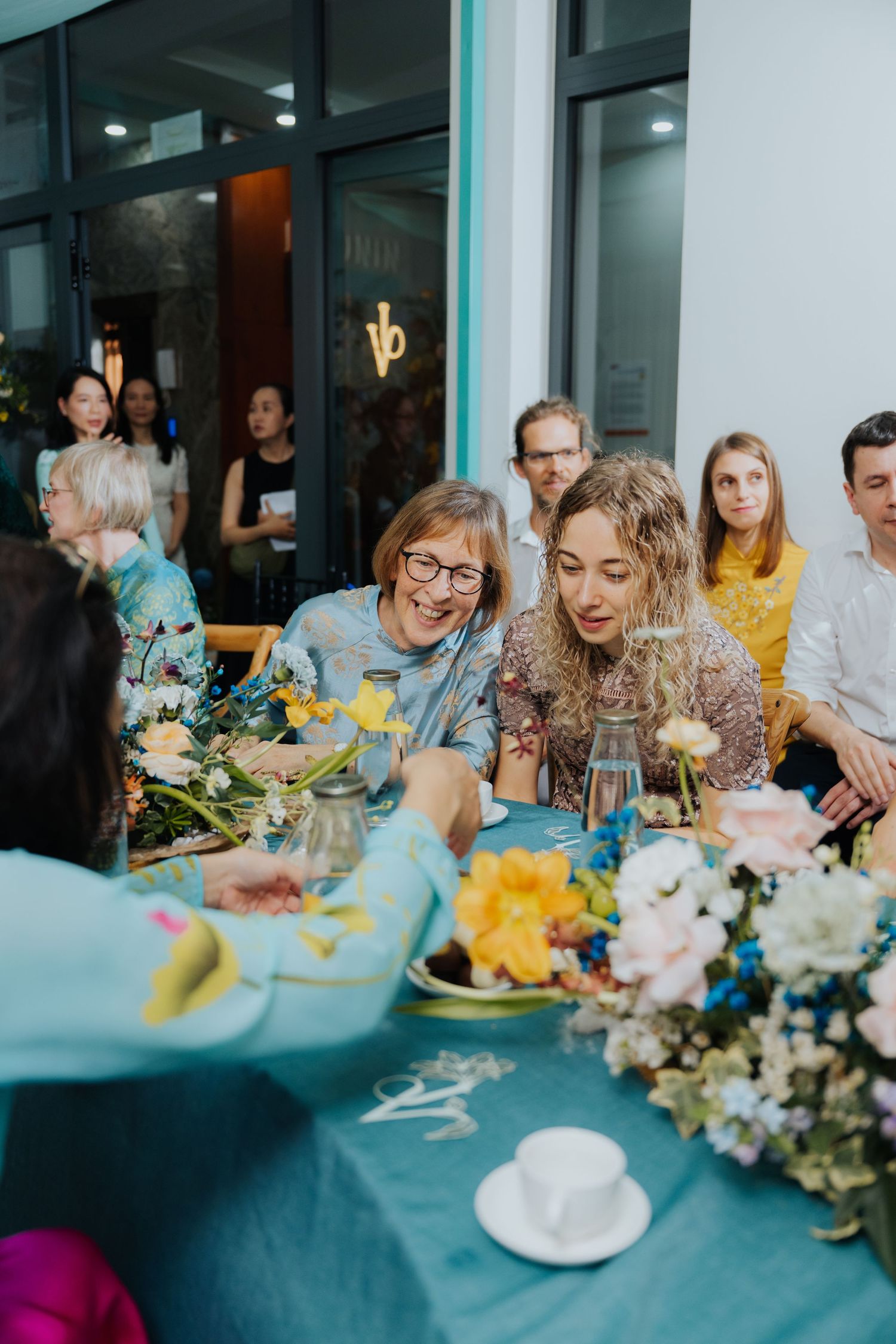 Guests gathered around a floral-decorated turquoise table at an elegant outdoor celebration.