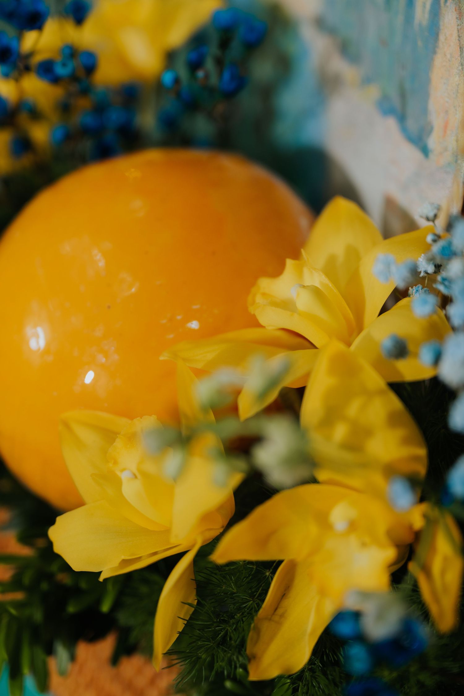 Close-up of a vibrant Easter arrangement with a yellow egg, daffodils, and blue berries.