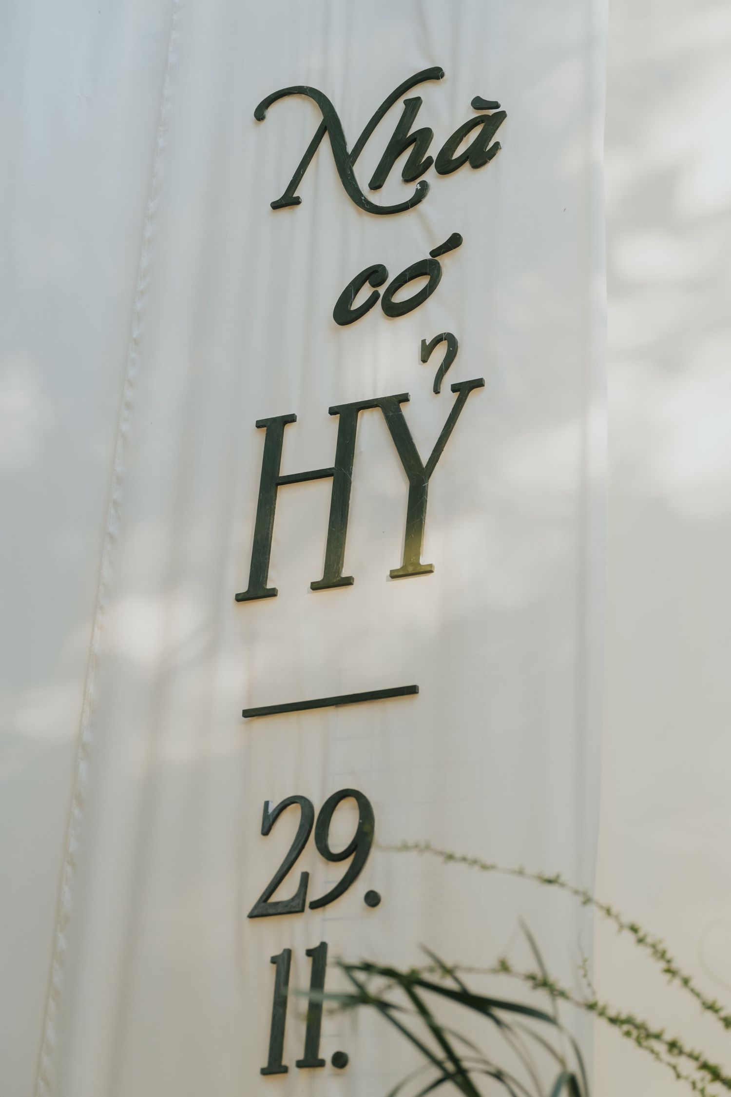 Vietnamese wedding sign reading Nha co Hy with date 29.11 mounted on white fabric backdrop.
