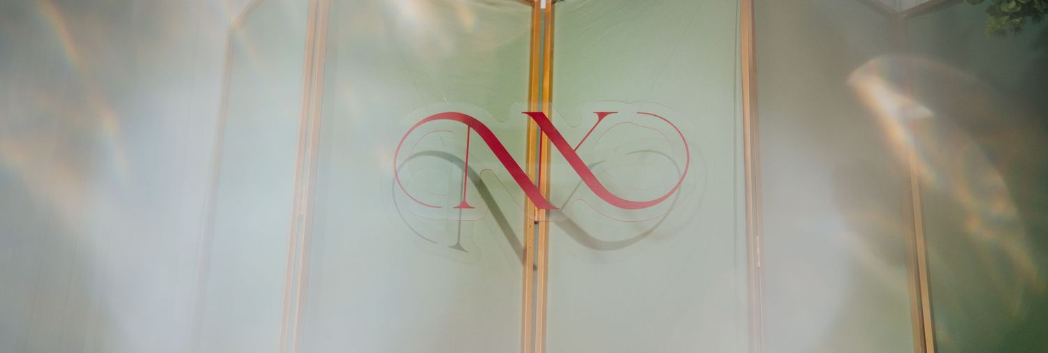 Frosted glass door panel featuring an elegant red and gold intertwined monogram logo in a luxurious interior setting.
