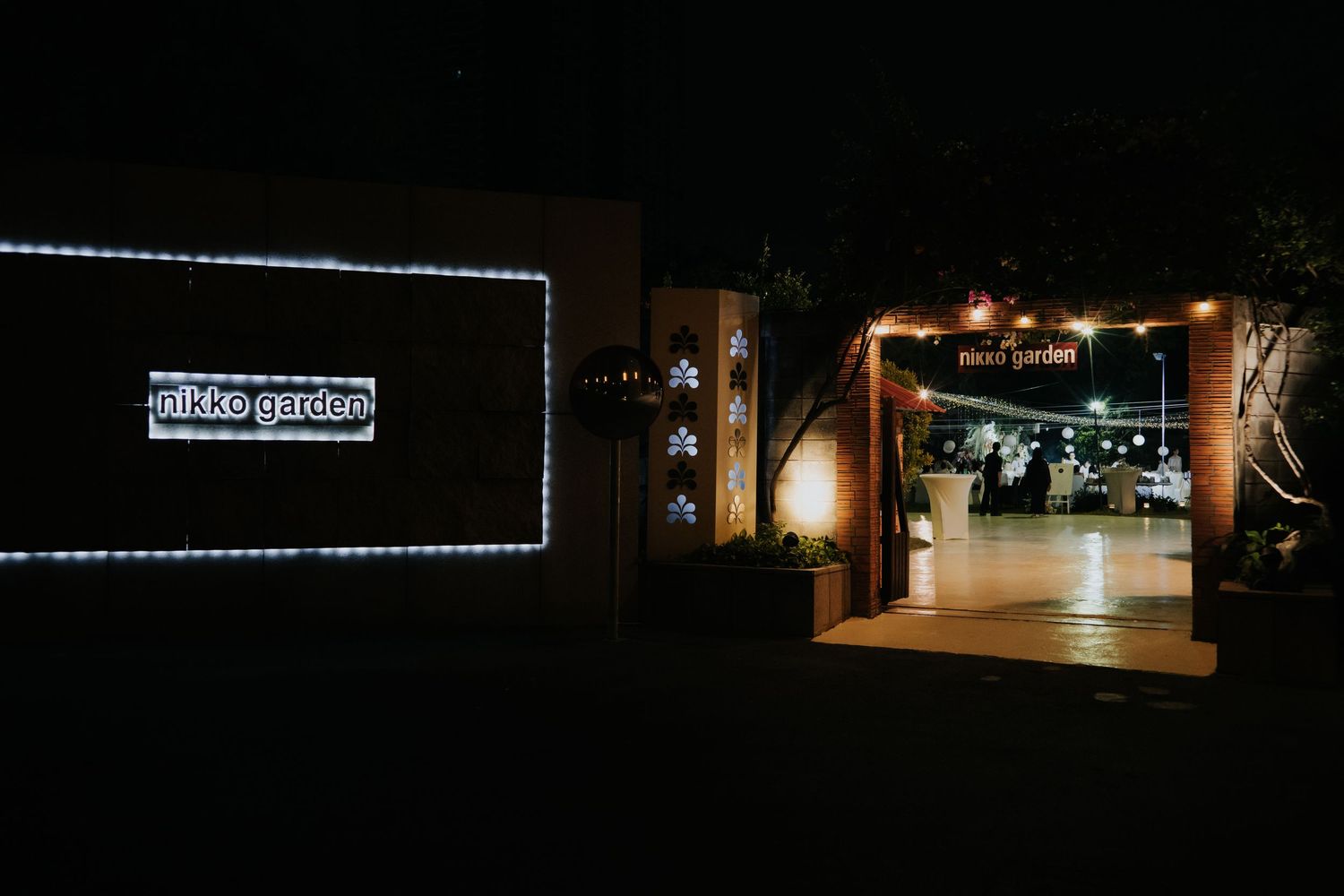 Nikko Garden venue entrance illuminated at night with fairy lights and warm glow welcoming guests.