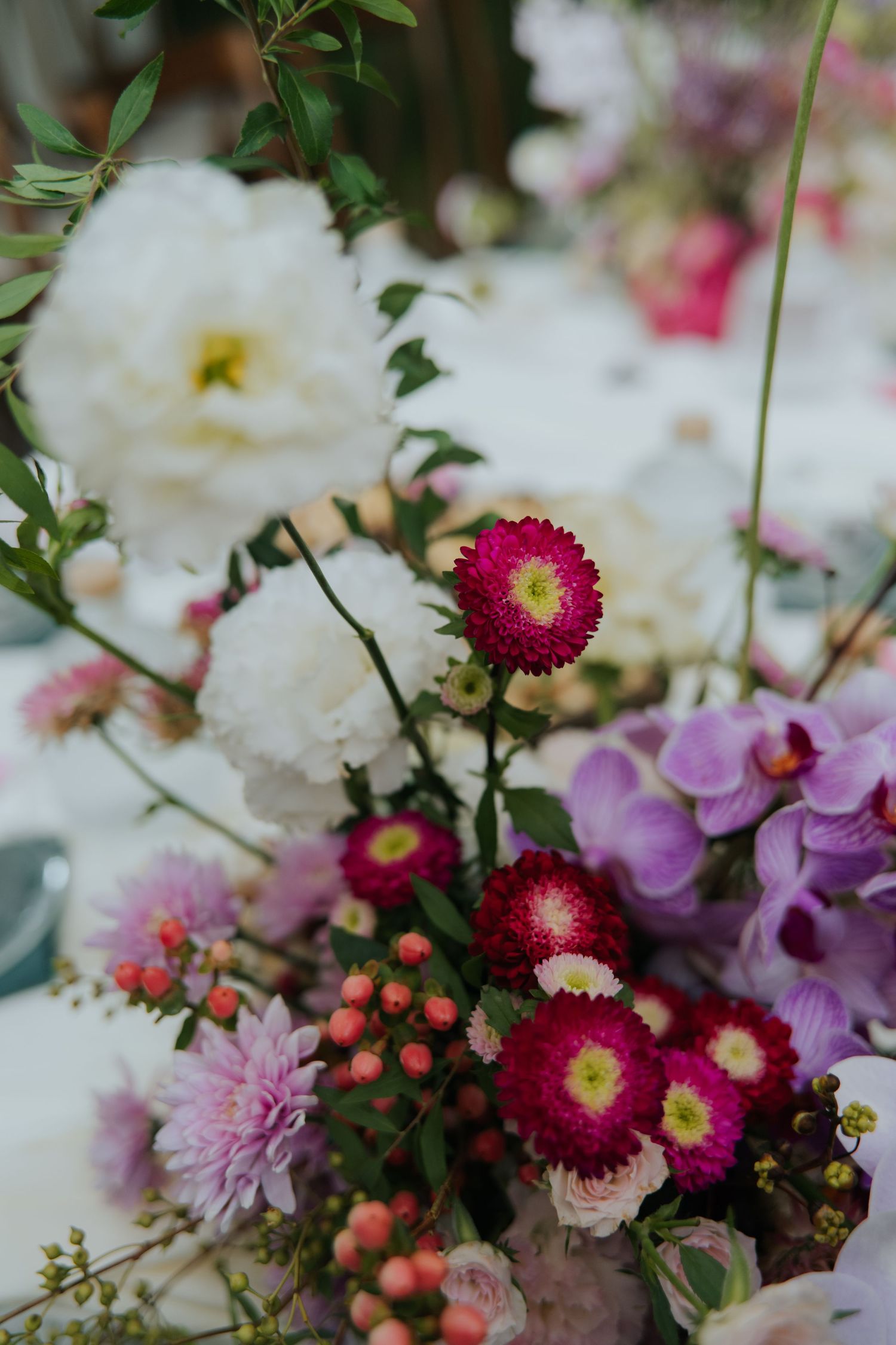 Vibrant floral centerpiece with pink, white, and purple flowers including dahlias and daisies for an elegant event.