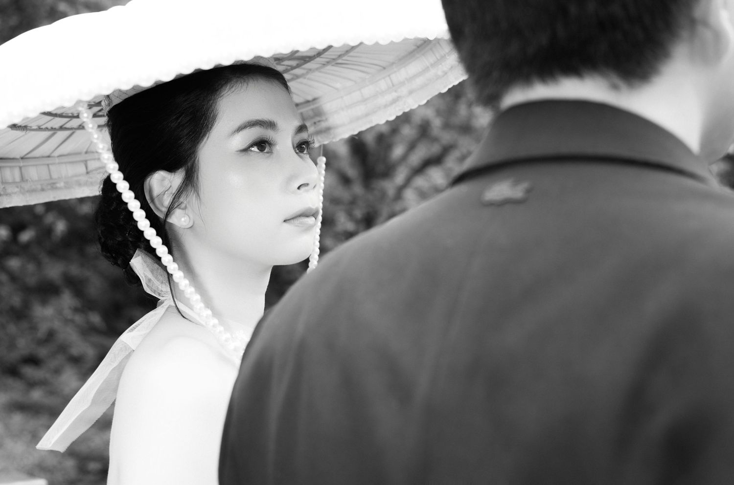 Black and white photo of a woman in a traditional white hat gazing at a man in a formal jacket.