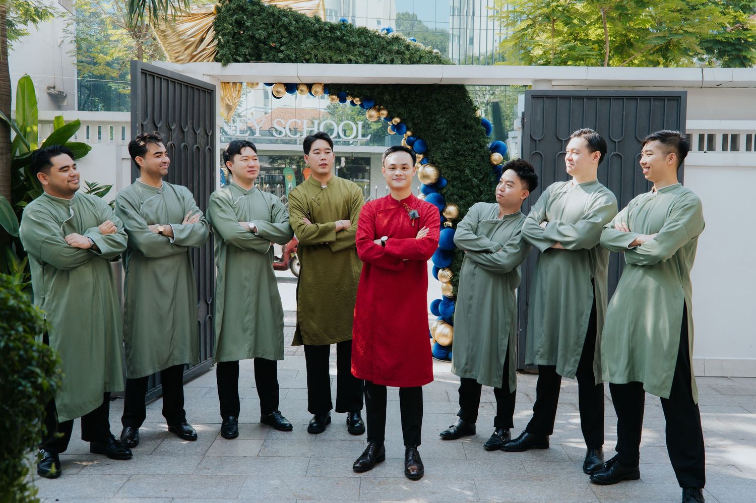 Group of men in traditional Vietnamese ao dai attire posing together outdoors at a festive celebration.