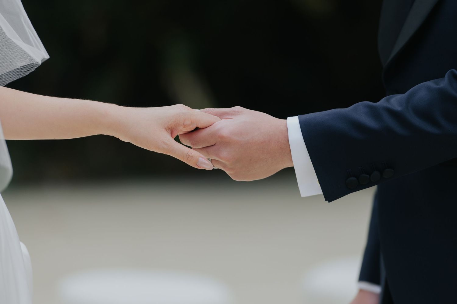 A bride and groom hold hands tenderly during their wedding ceremony, symbolizing love and commitment.
