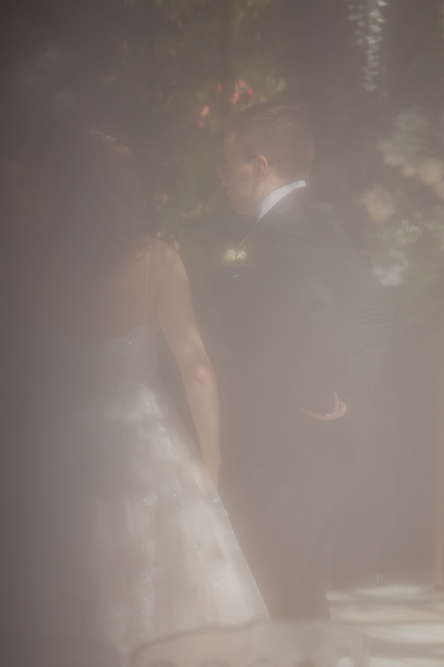 Dreamy misty photo of bride and groom sharing an intimate moment at wedding ceremony.