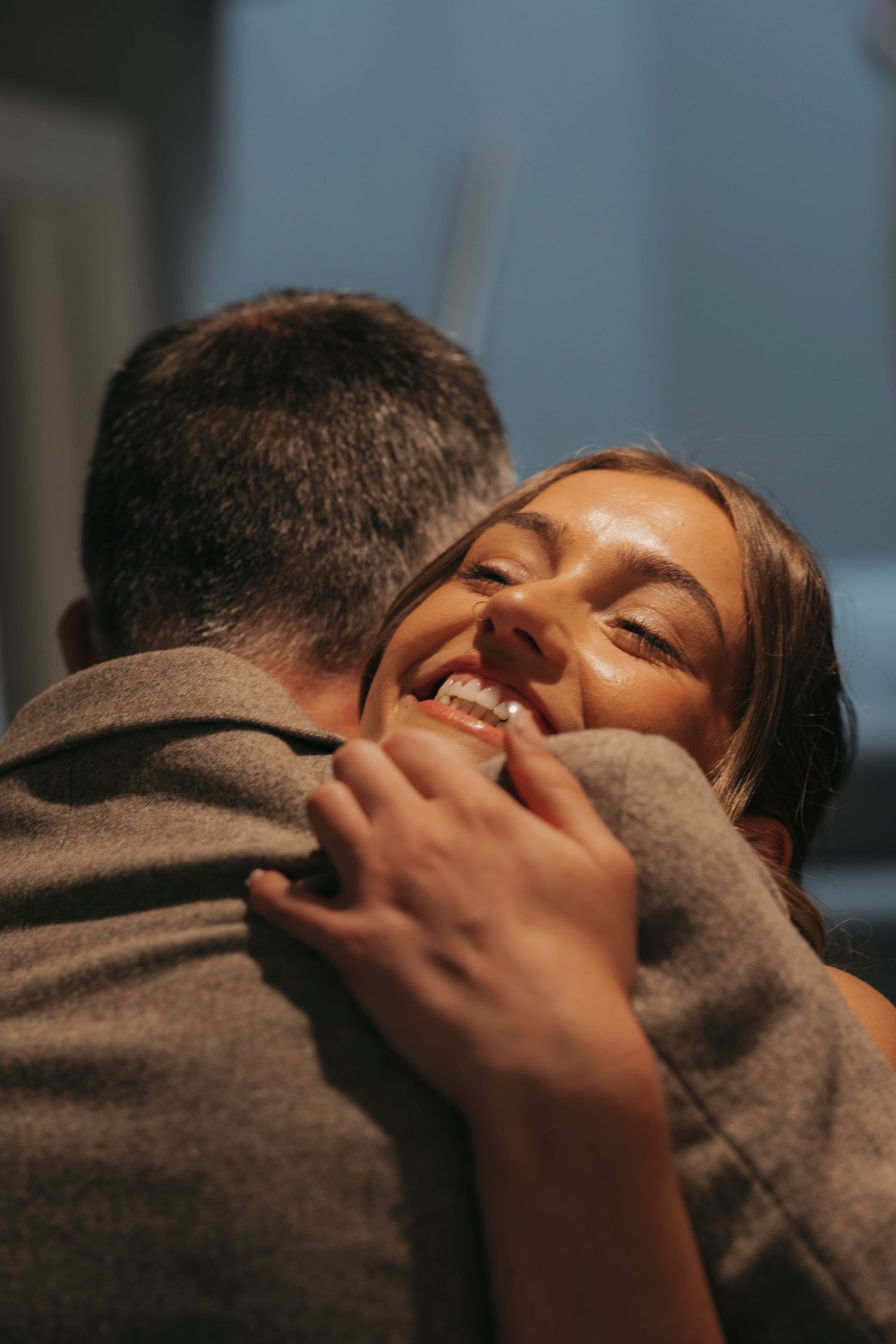 A smiling woman embraces a man in a warm, affectionate hug during an intimate wedding moment.