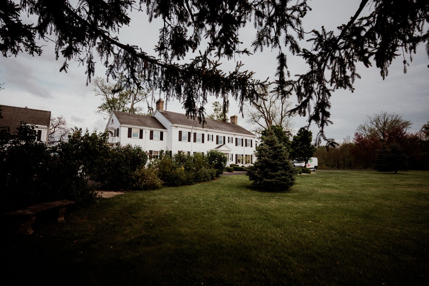Large white colonial mansion set on a hillside surrounded by evergreen trees. The christy house, fremont, ohio