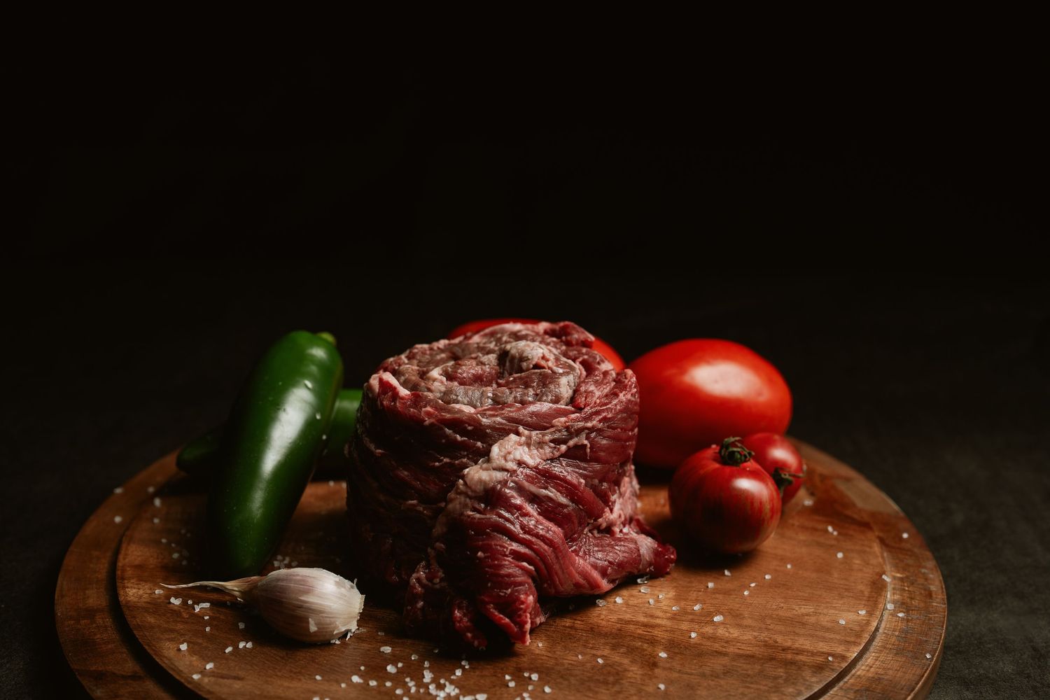 Raw meat and fresh vegetables arranged on a rustic wooden cutting board. AP Cattle Co, Clyde ohio