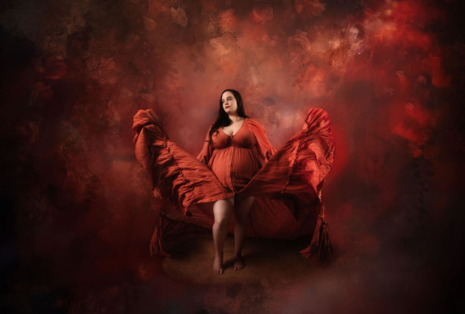 Artistic maternity photo with flowing red fabric against dark dramatic background. Clyde ohio