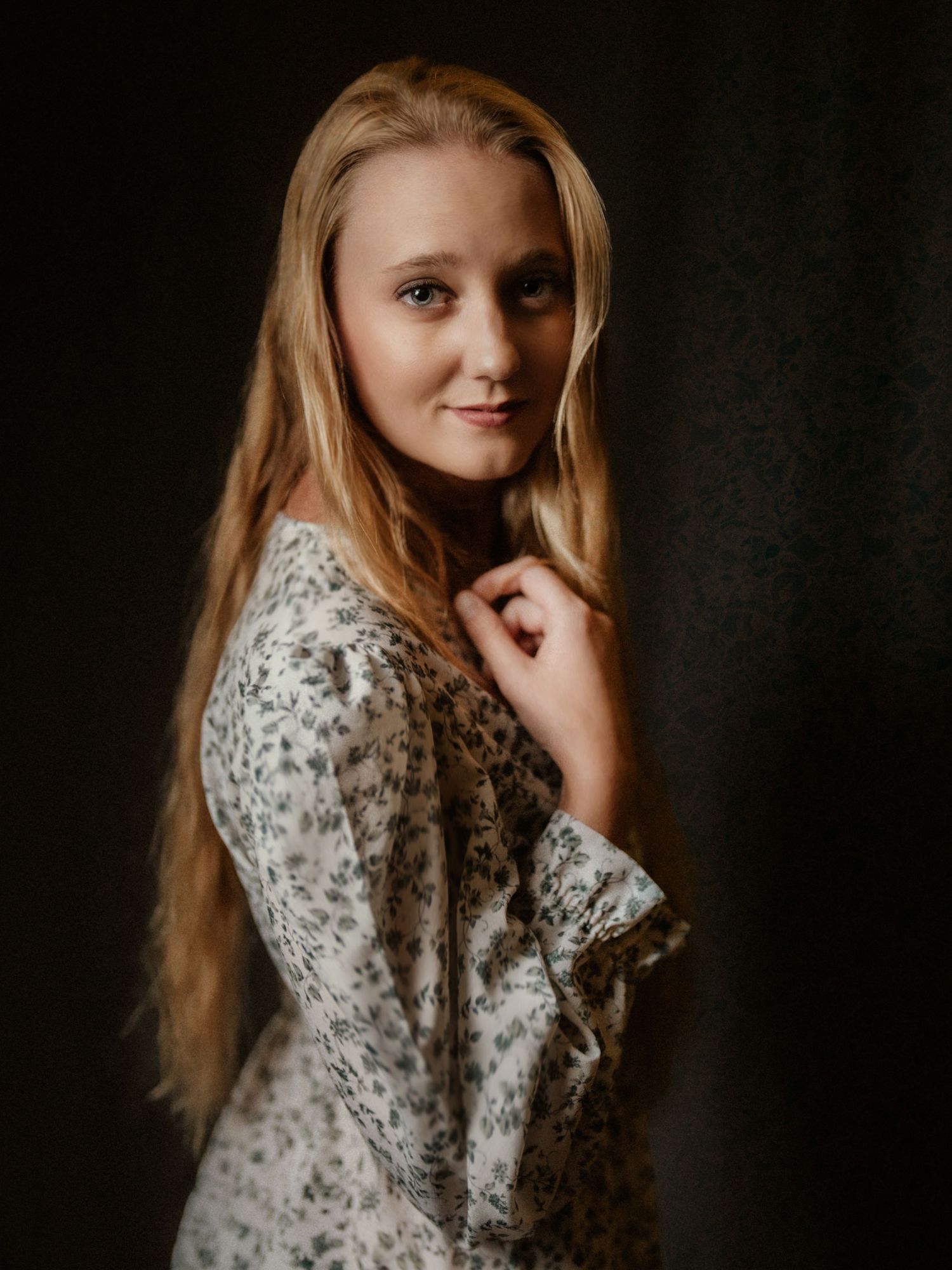 Moody portrait in floral dress against dark background with dramatic lighting.  Clyde, Ohio
