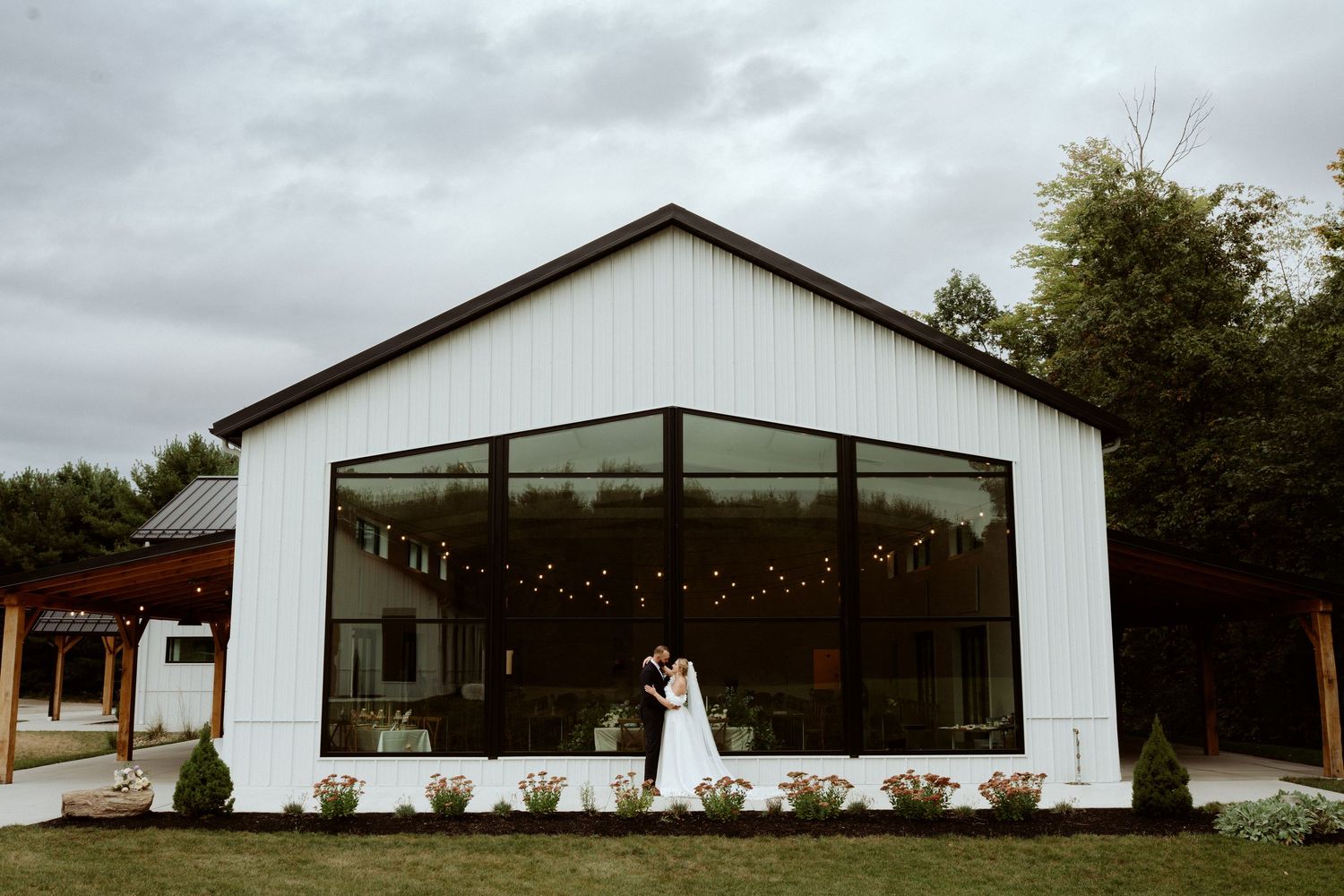 A modern white wedding venue with string lights and clean architectural lines photographed at dusk. Wooster Ohio The Wellspring Wedding