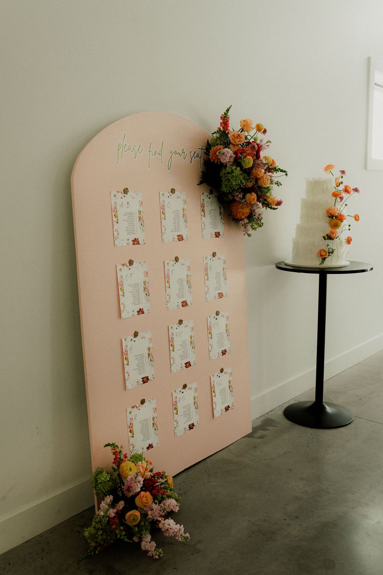 Pink seating chart display decorated with colorful floral arrangements. Wooster Ohio The Wellspring Wedding Venue