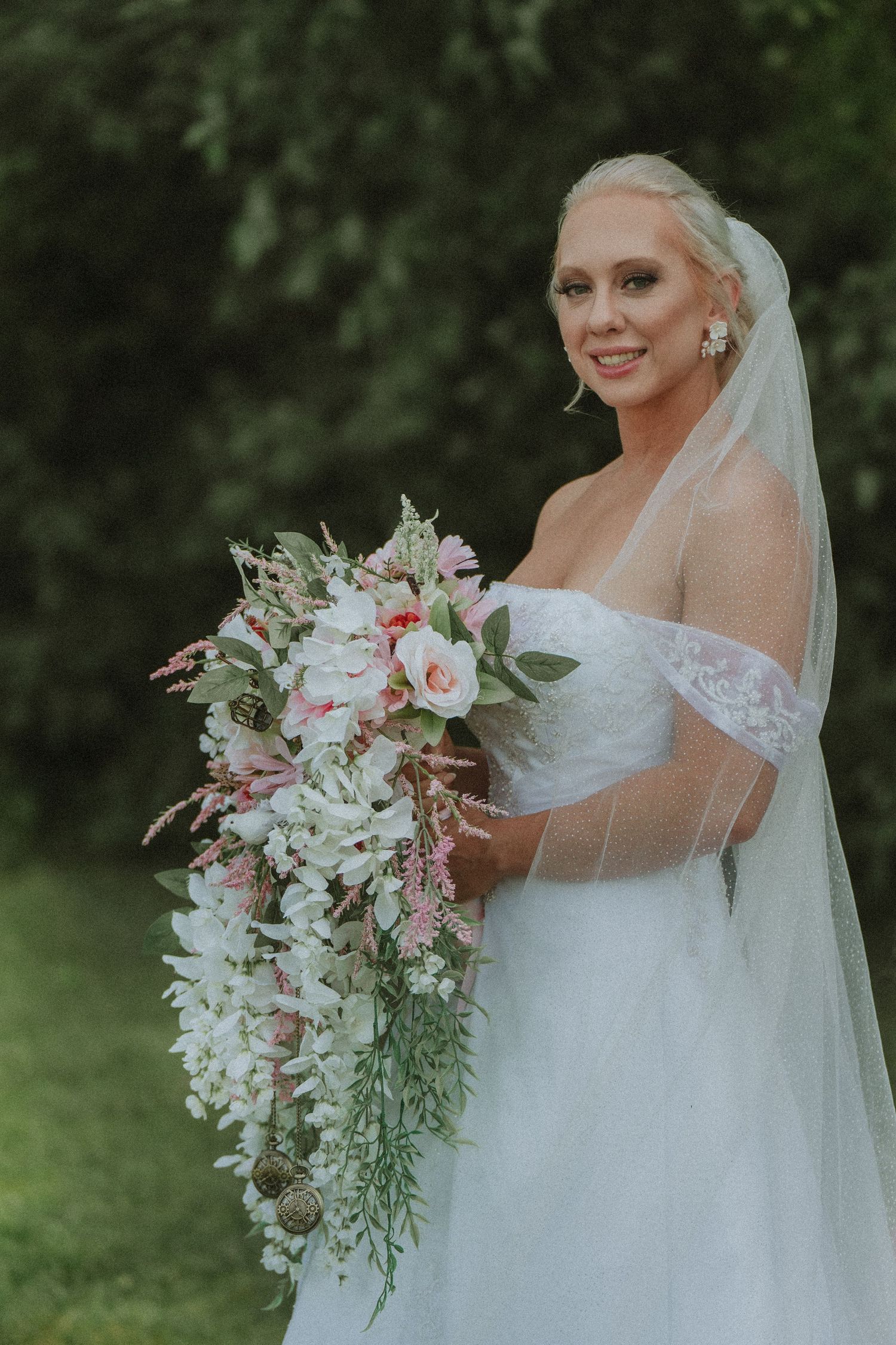 A bride in a white off-shoulder gown holds a cascading bouquet of pink and white flowers. Clyde, Ohio copper whale winery