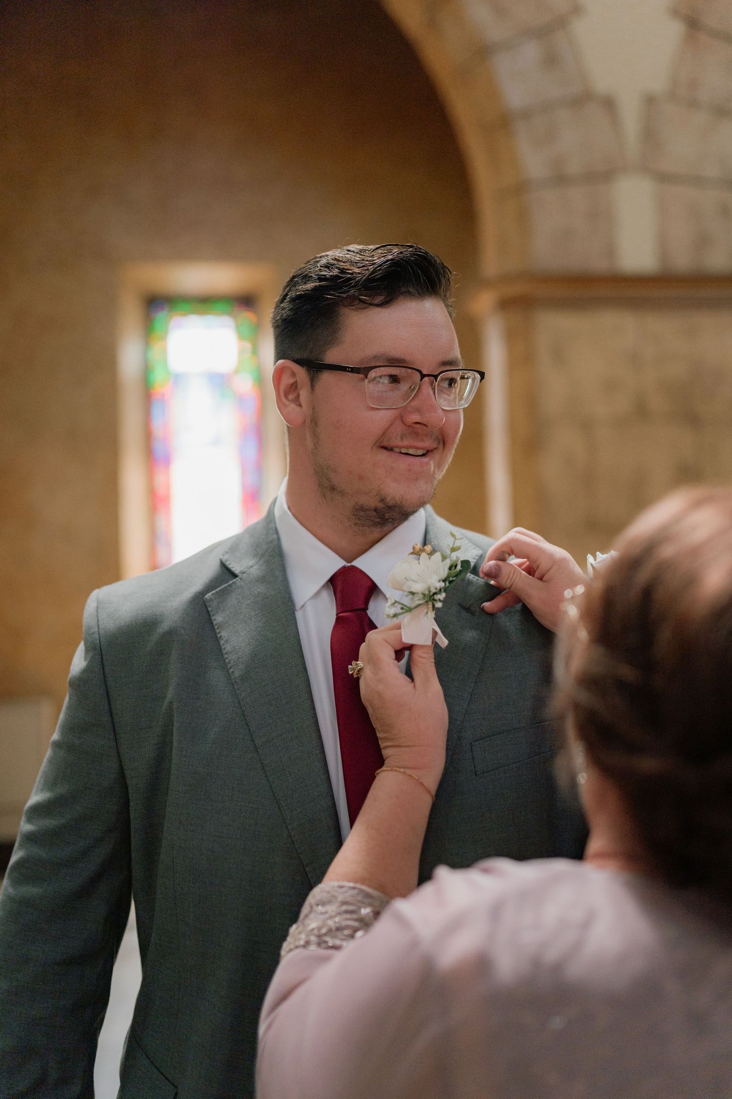 A touching moment during a wedding ceremony as a boutonniere is pinned on a grey suit. Tiffin, Ohio Wedding Venue