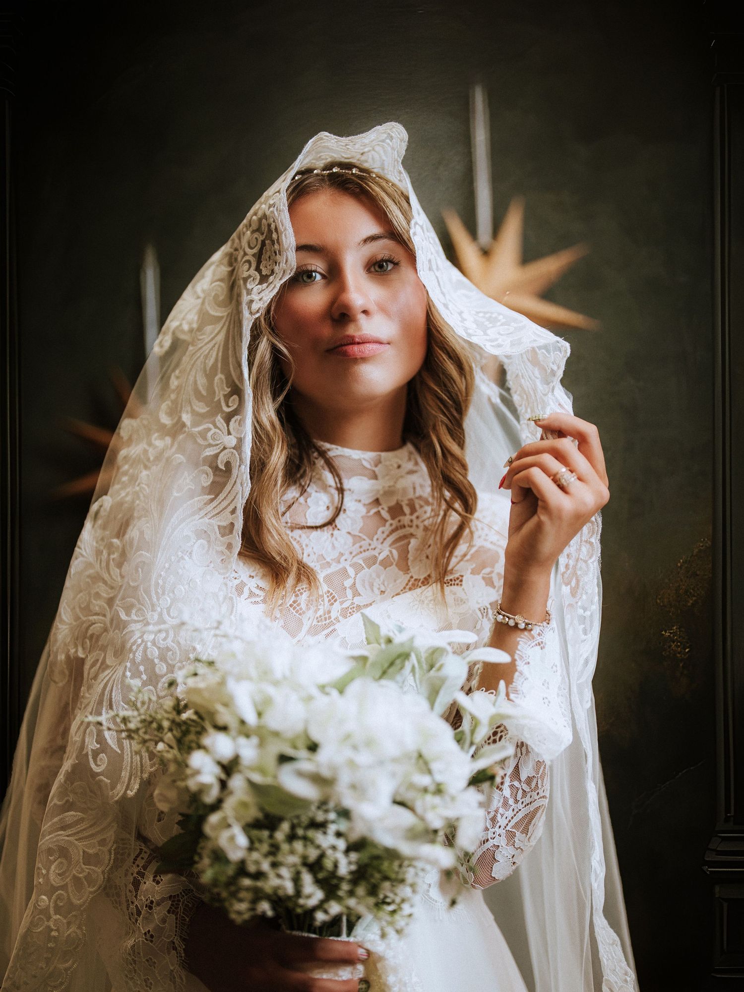 Bridal portrait featuring lace veil and white floral bouquet against dark background. Clyde ohio