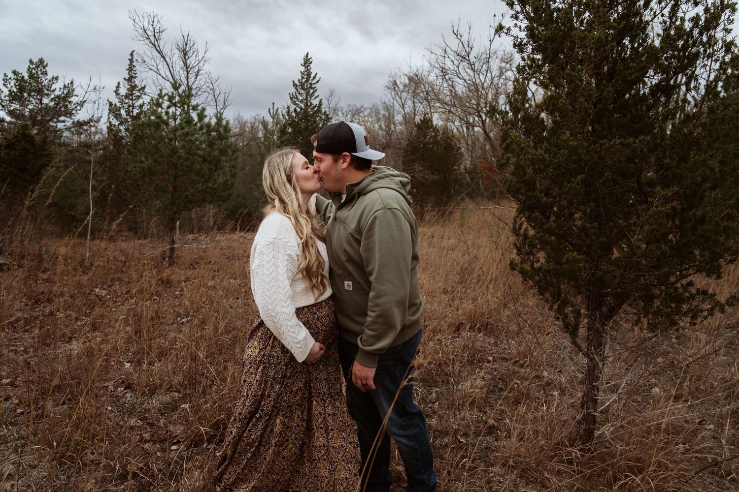 A couple shares an intimate moment against a moody winter landscape with evergreen trees in the background. Castalia Quarry, Ohio