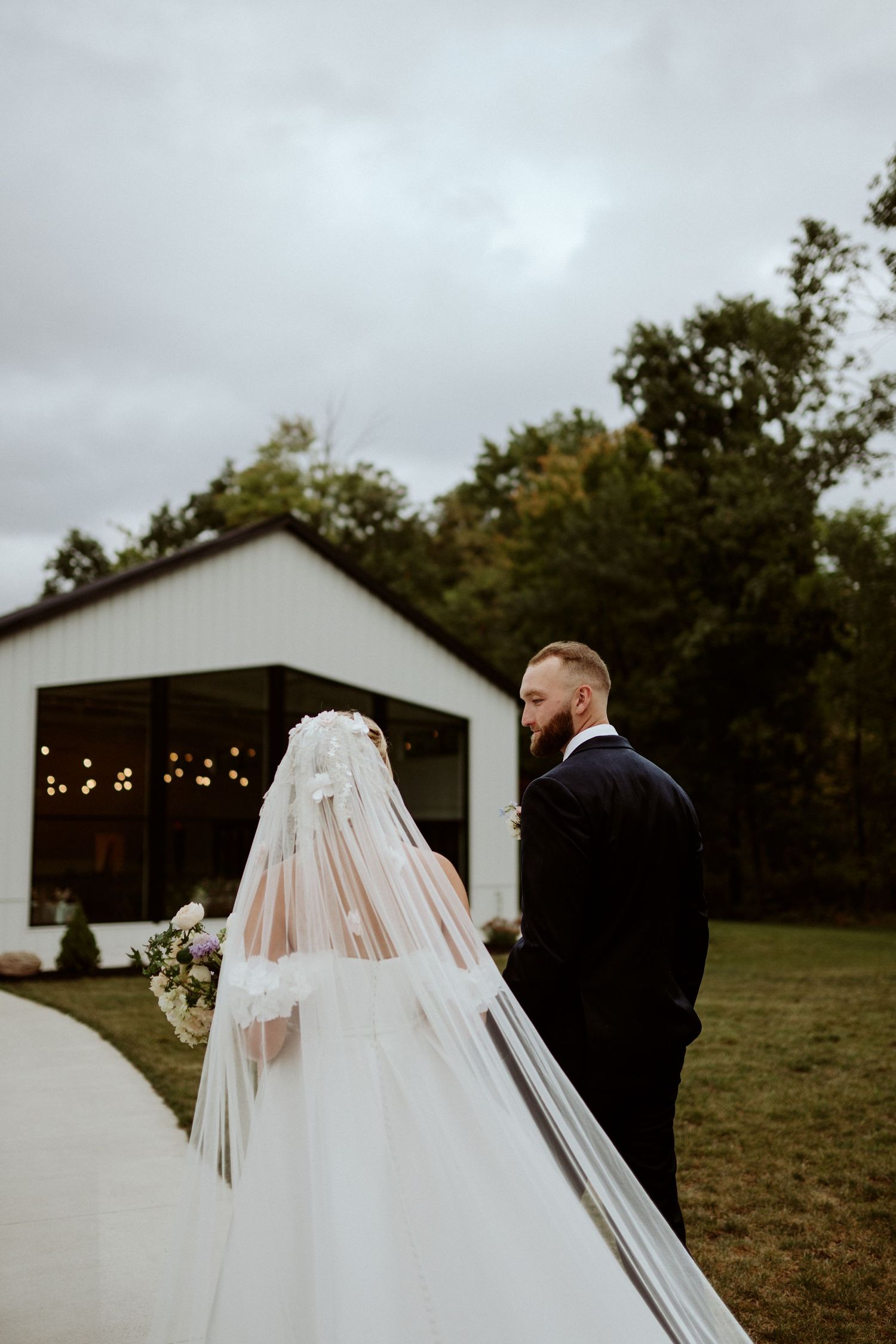 A wedding couple shares an intimate moment outside a modern white venue. Wooster Ohio The Wellspring Wedding Venue