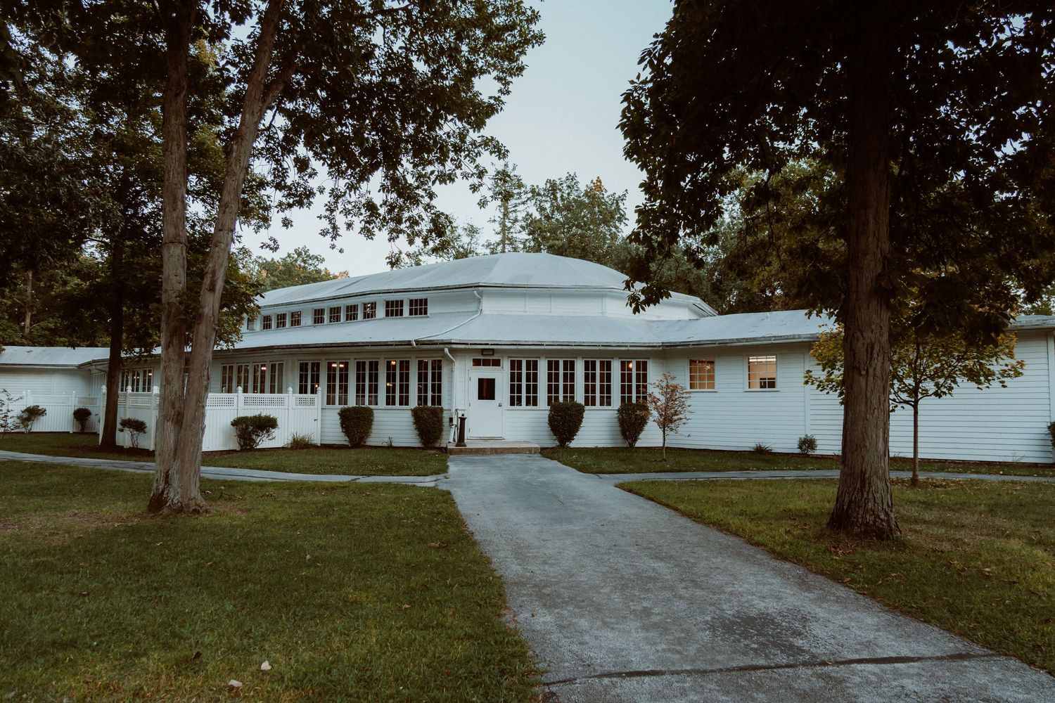 Long driveway leading to white buildings surrounded by trees in a rural setting. Bascom, Ohio wedding venue Meadowbrook