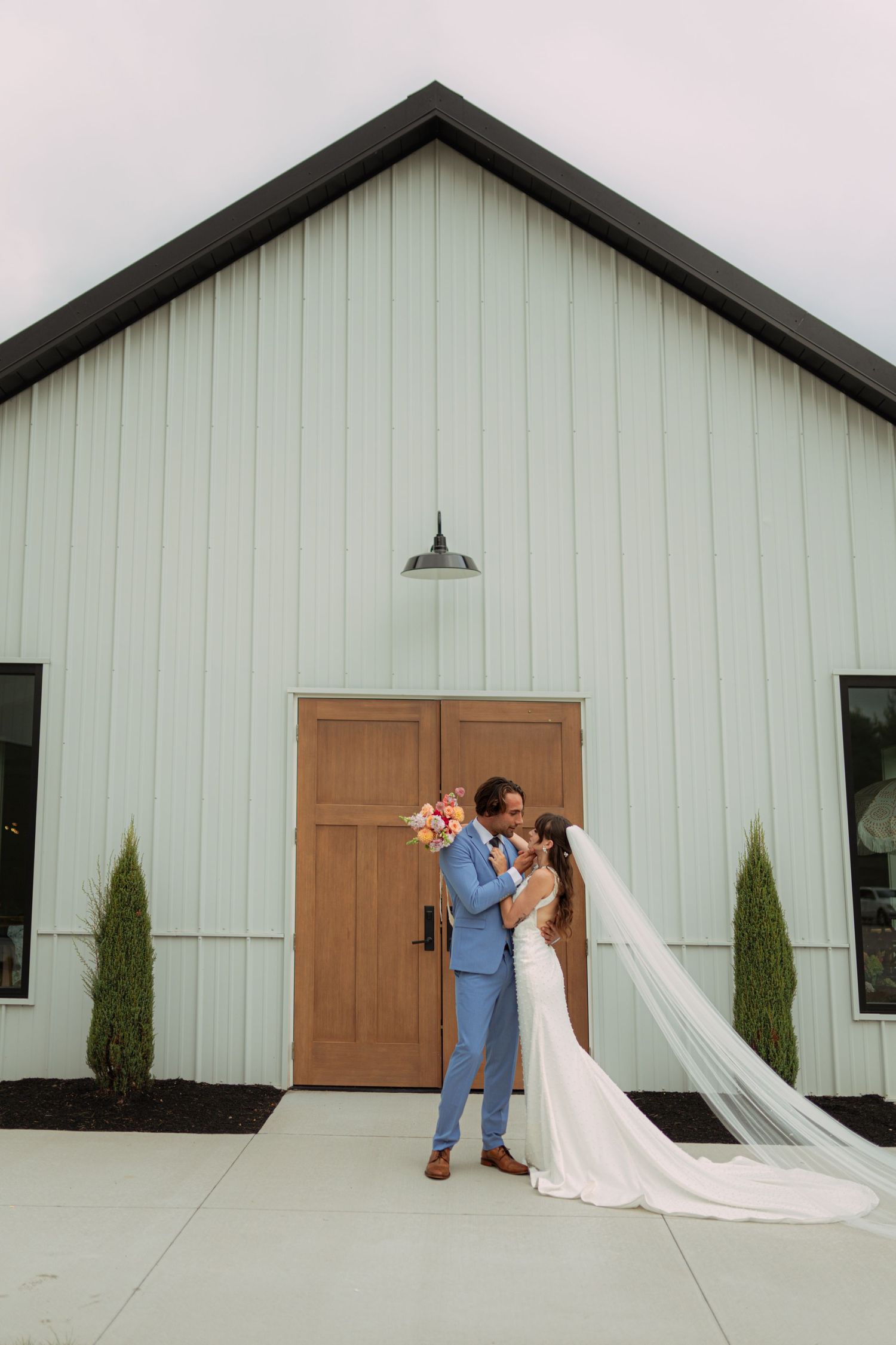 A romantic wedding photoshoot sequence in front of a white barn with cypress trees. Wooster Ohio The Wellspring Wedding Venue