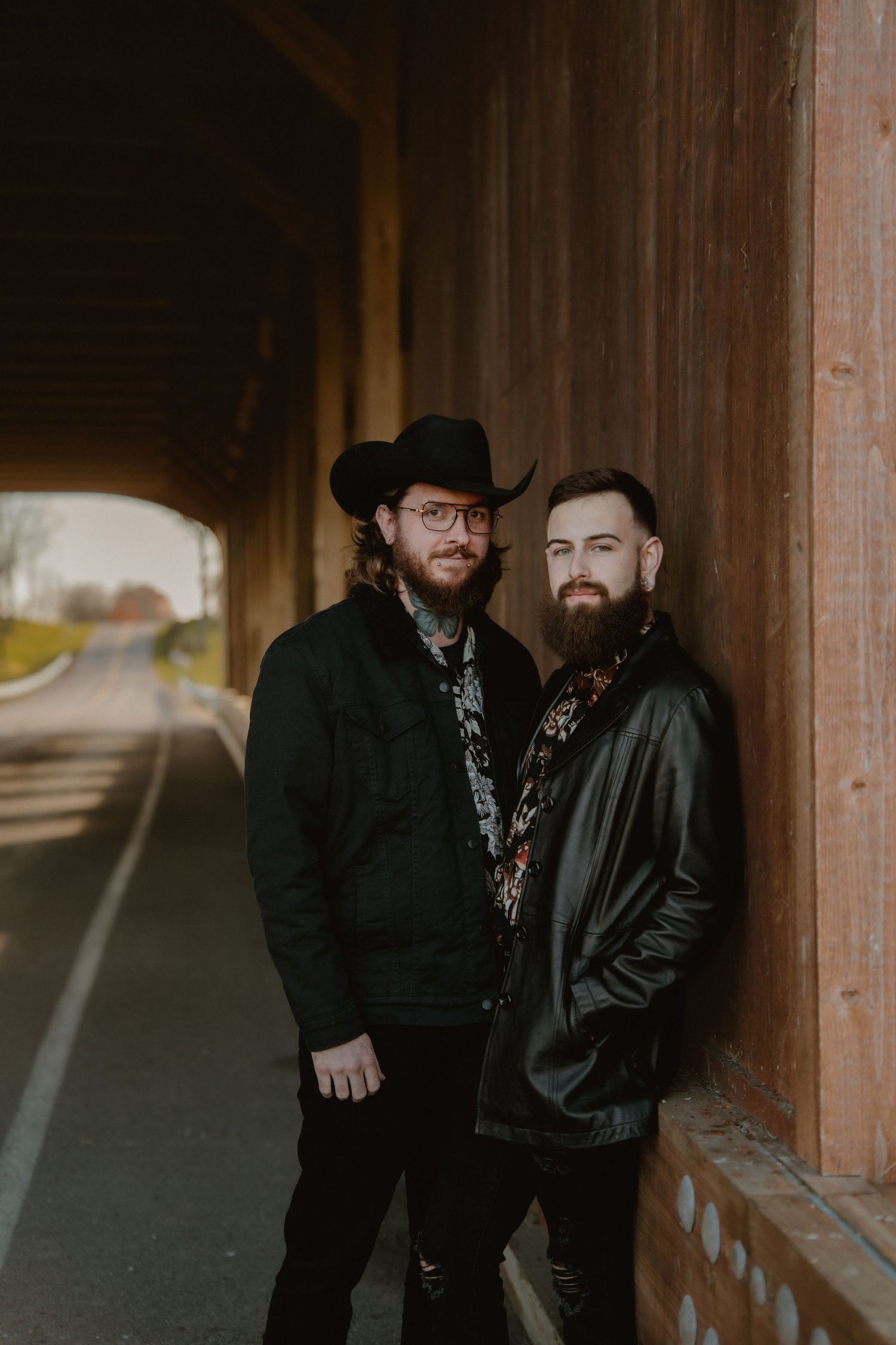 Two people in black attire pose together under a wooden covered walkway in dramatic lighting. Marion, Ohio